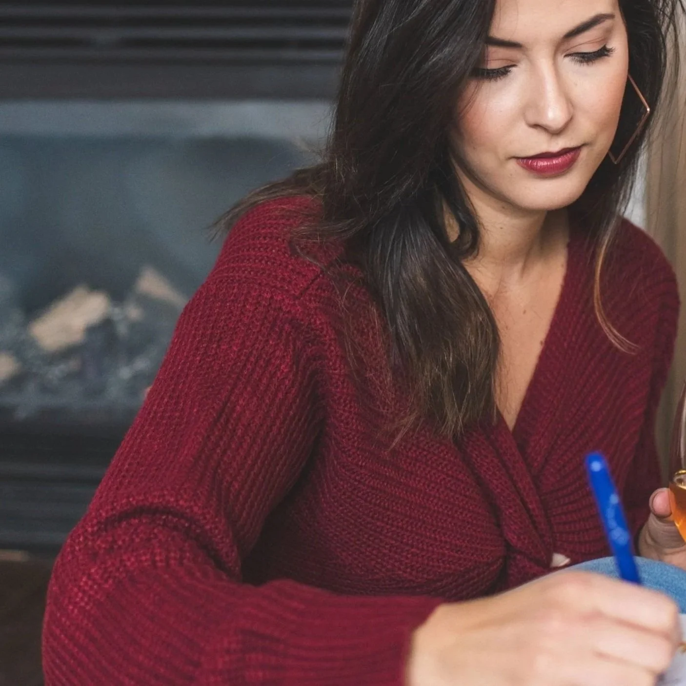 Becca Grieb, Fractional CMO writing with a pen at a table, with a fireplace in the background.