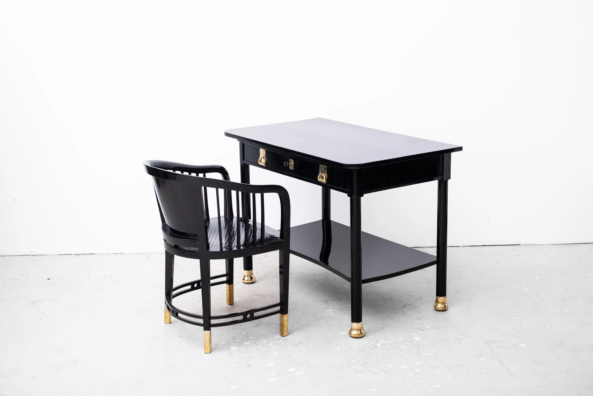 Schwarzer Schreibtisch mit goldenen Akzenten und passendem Stuhl auf hellem Hintergrund.