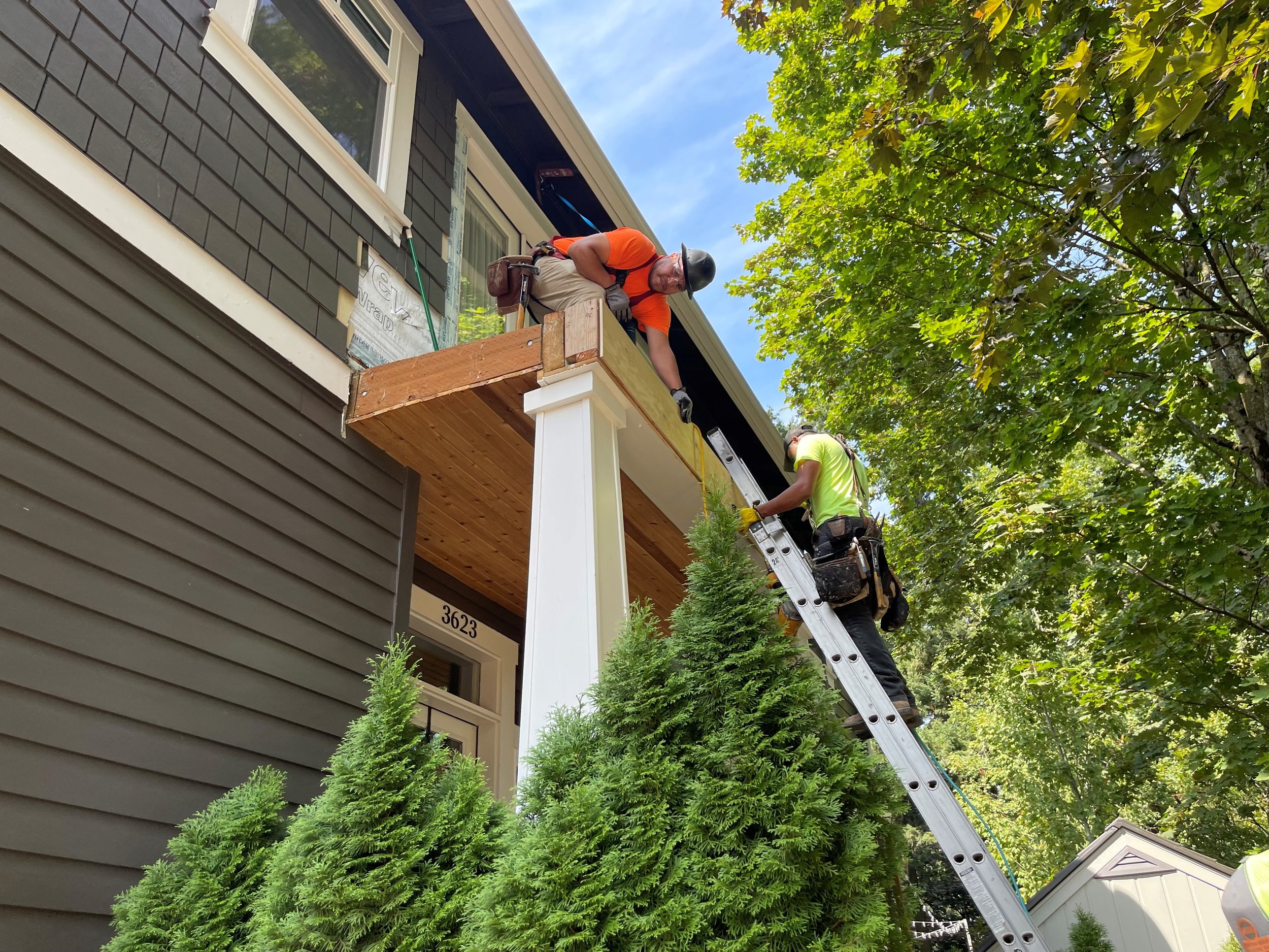 L&A construction worker climbing a ladder to finish siding on a residential siding job