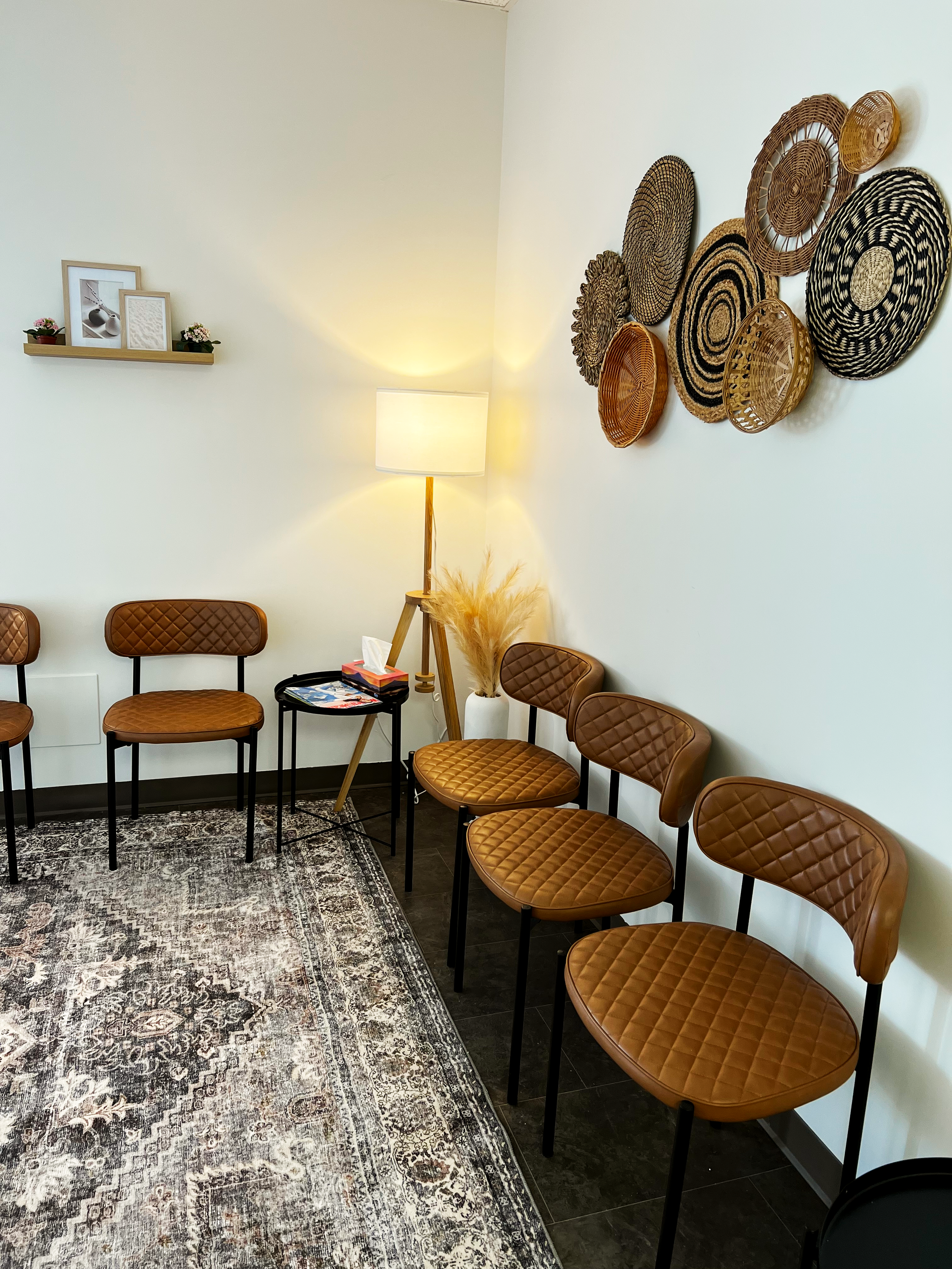 Waiting room with brown leather chairs, vintage rug, basket wall decor