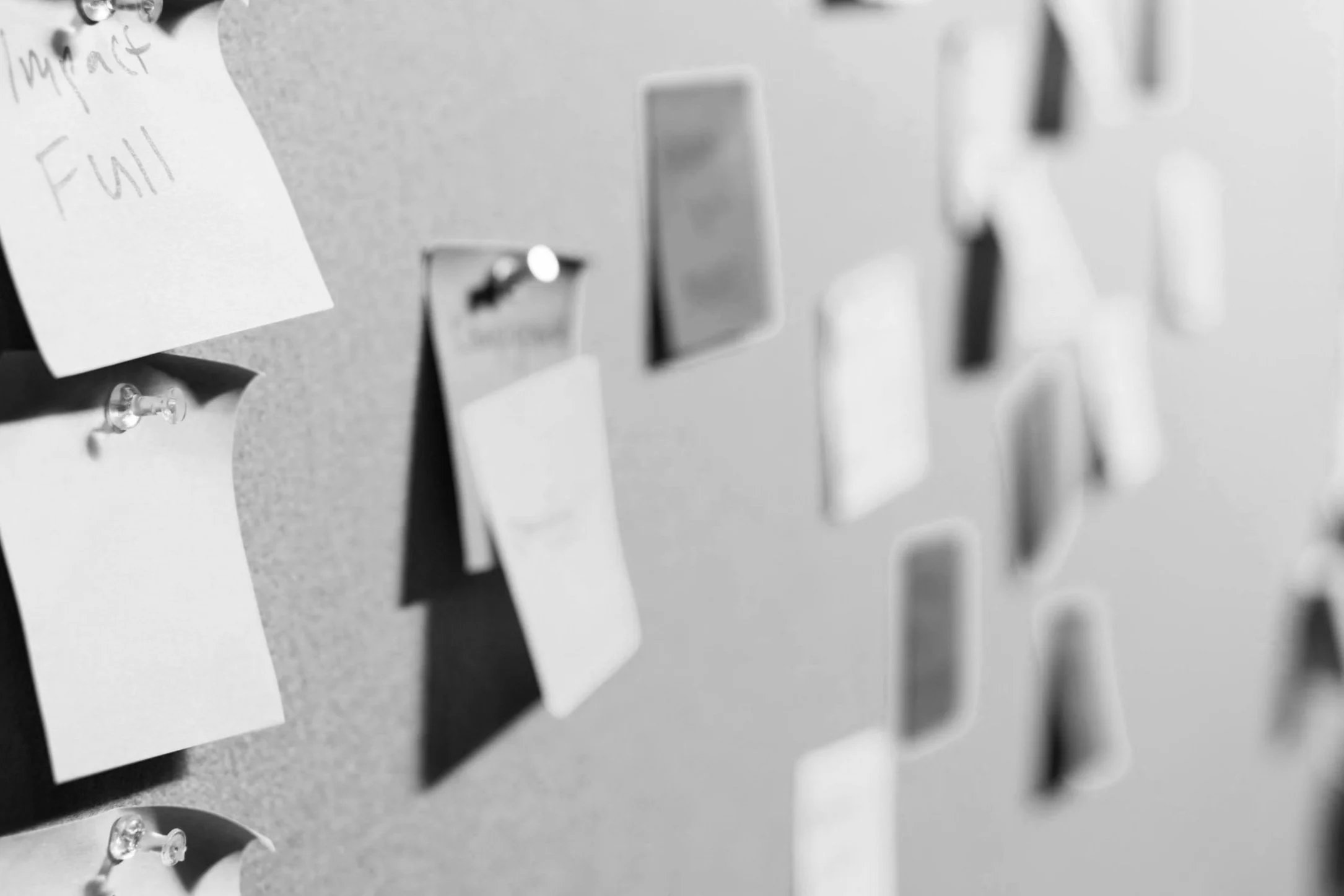 A collection of sticky notes attached to a gray bulletin board, some with handwritten notes.