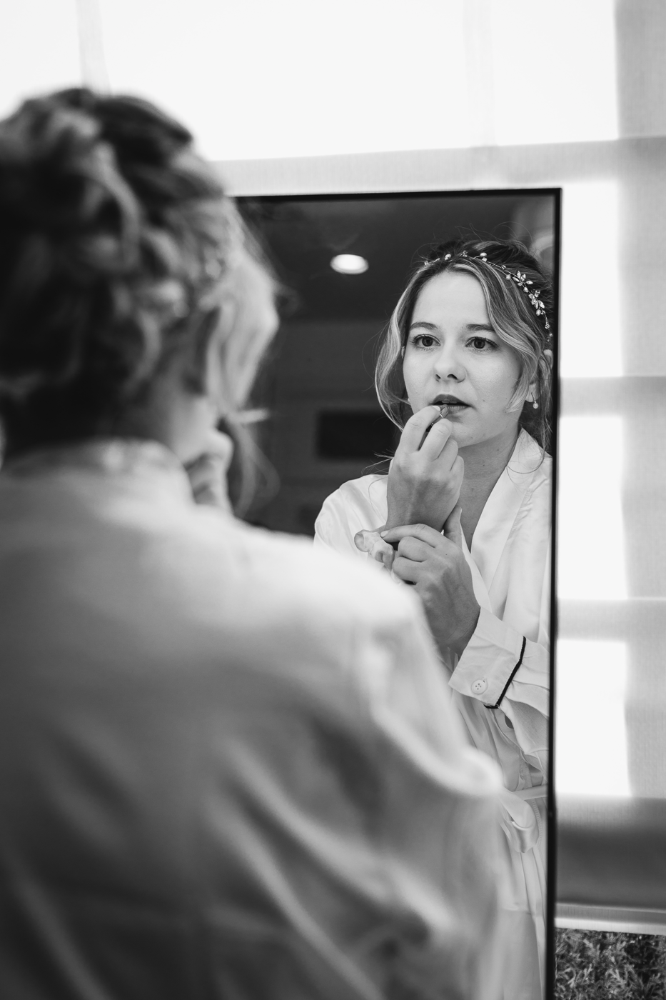Bride puts on lipstick in the mirror as she gets ready for her fingerlakes wedding