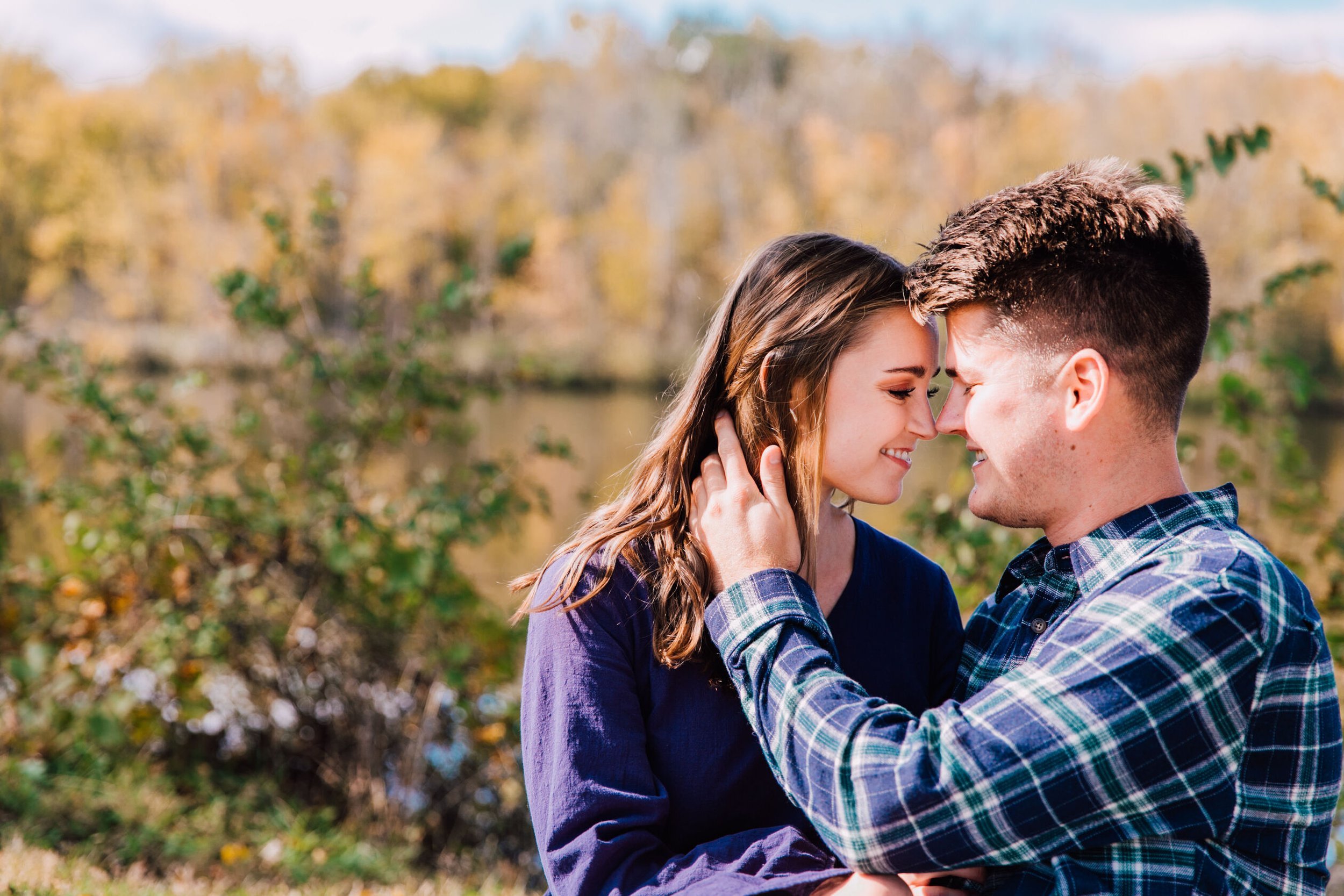  engaged couple smile at each other during fall engagement photos 