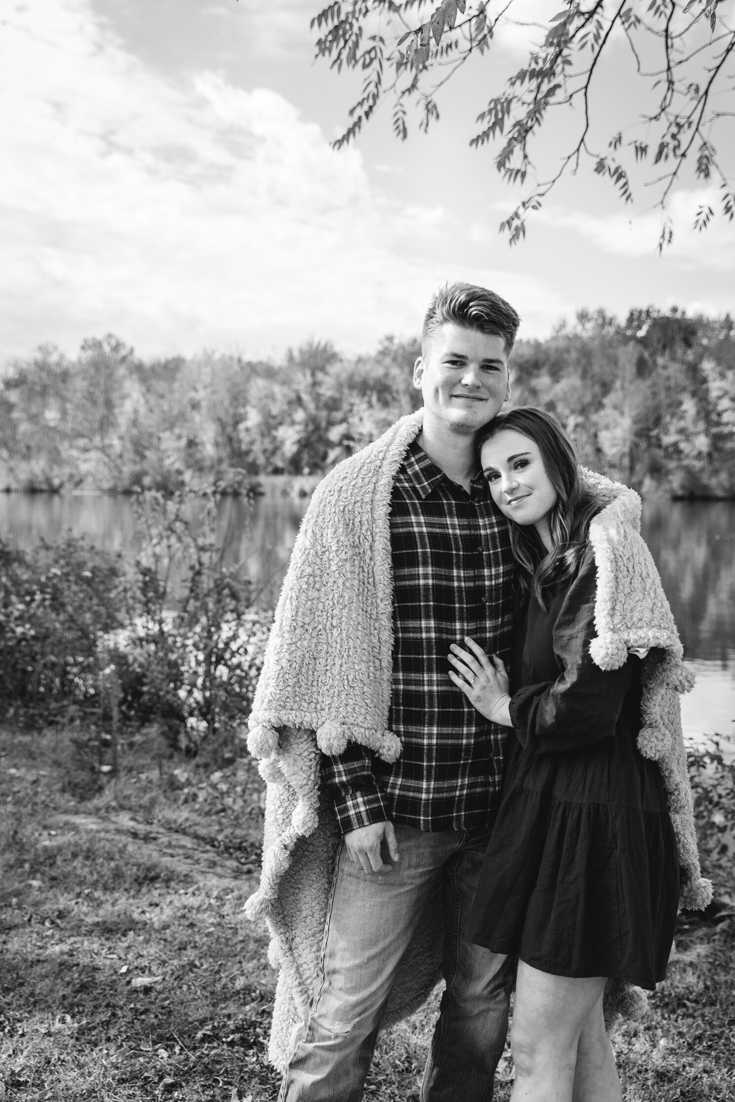  engaged couple stand cuddled up with a blanket at their engagement session 