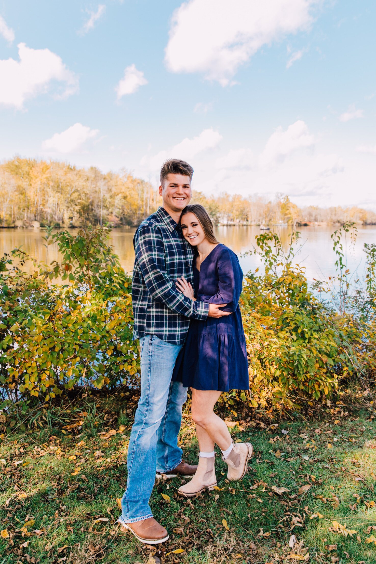  newly engaged couple smile together in front of a lake in central ny 