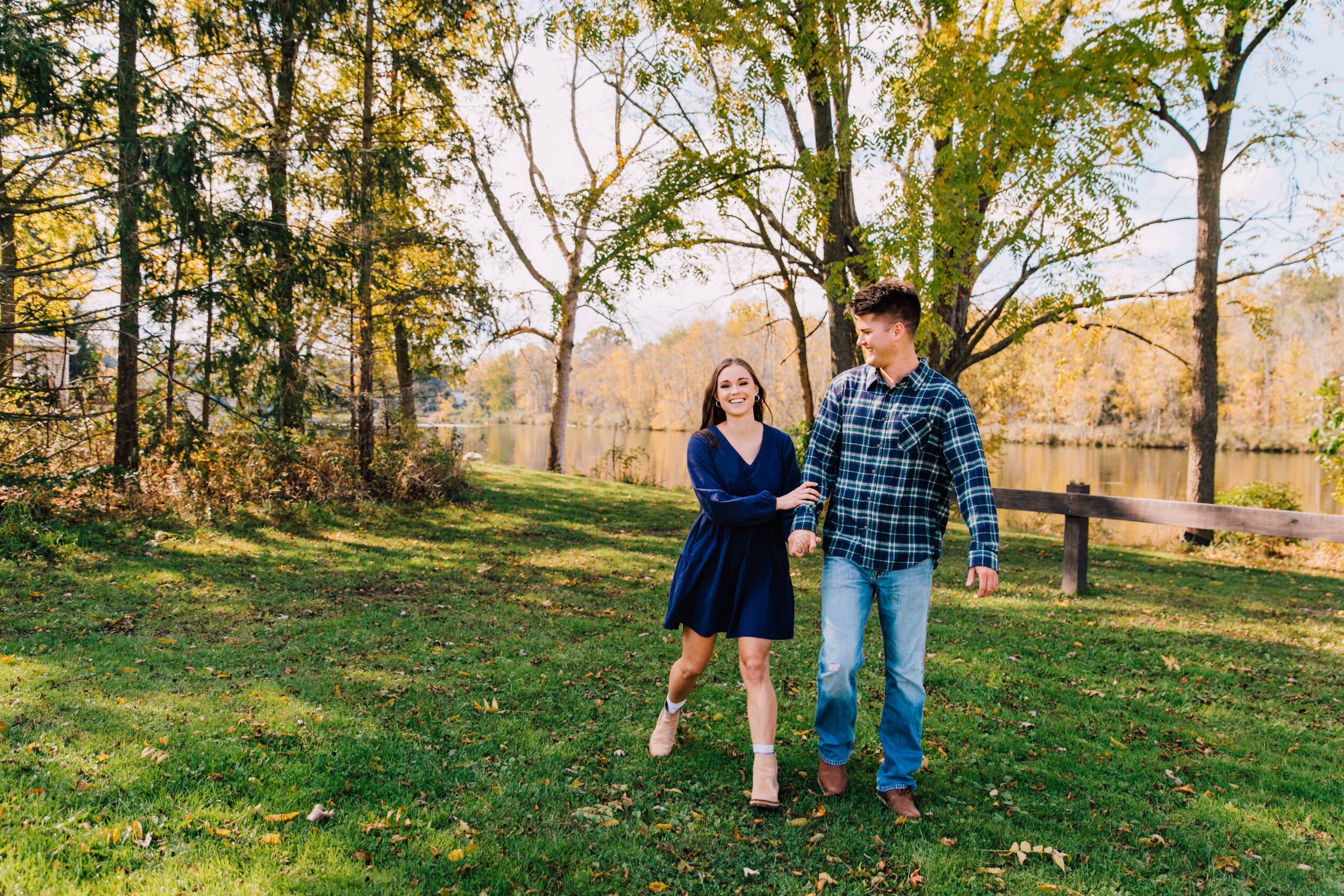  couple smiles as they walk together during their fall engagement photos 