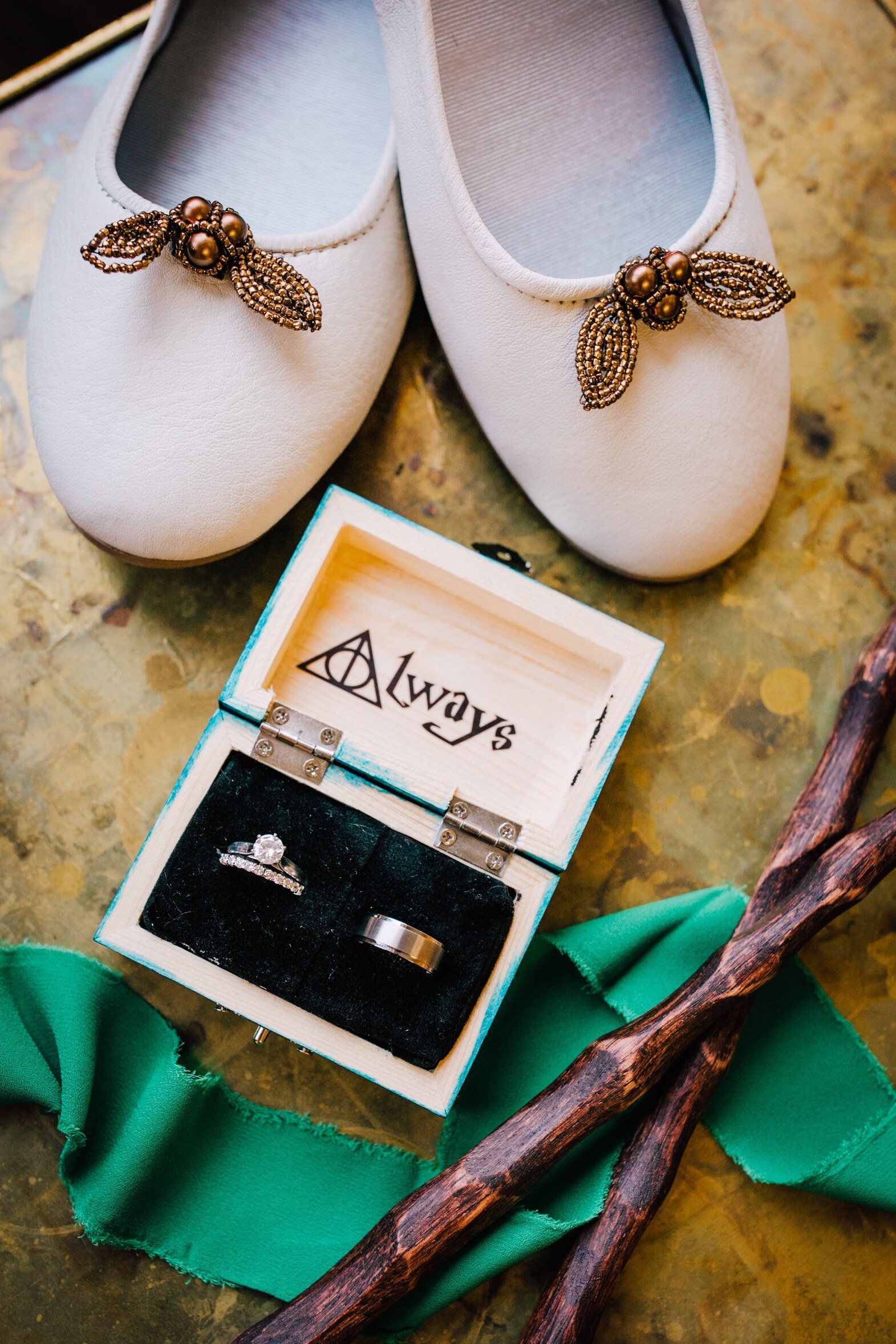  the bride’s shoes, the couple’s rings, and harry potter wands lay flat before the couple’s harry potter wedding 