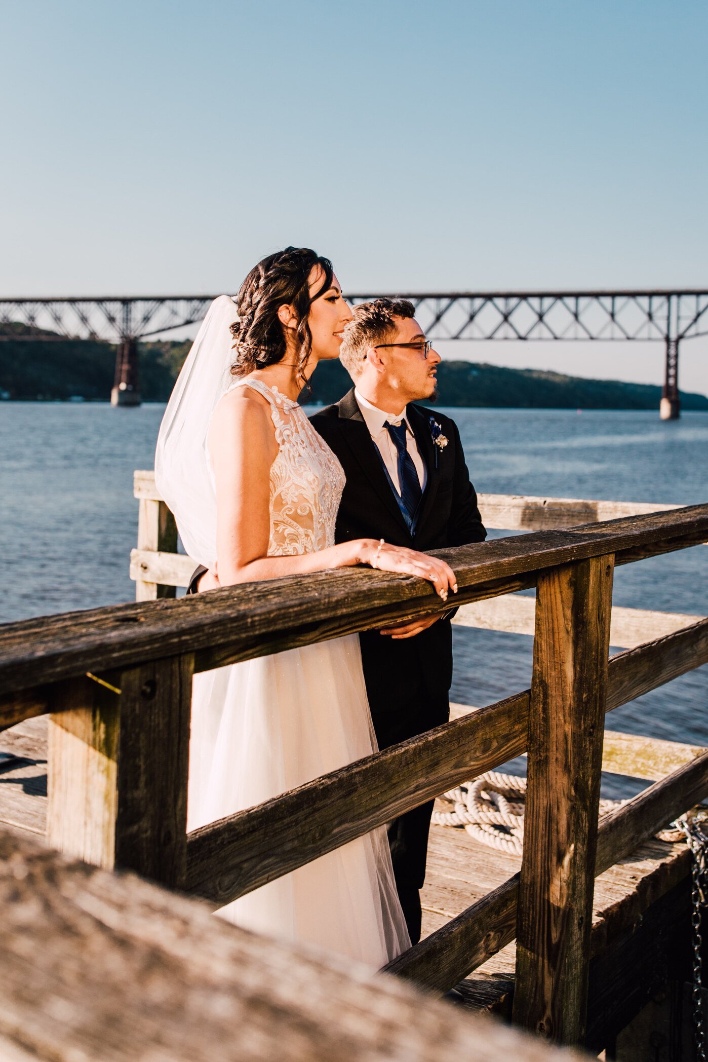  the bride and groom look out over a pier before their hudson river wedding 