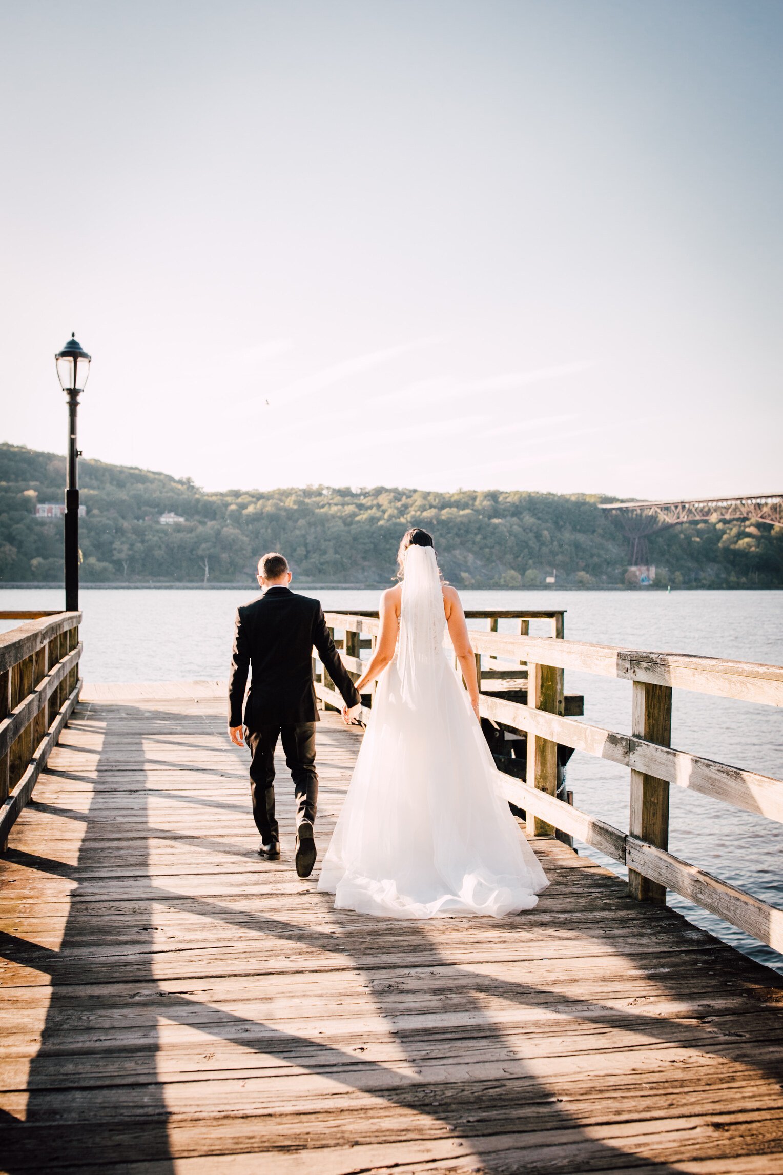  a bride and groom walk down a boardwalk before their hudson river wedding   