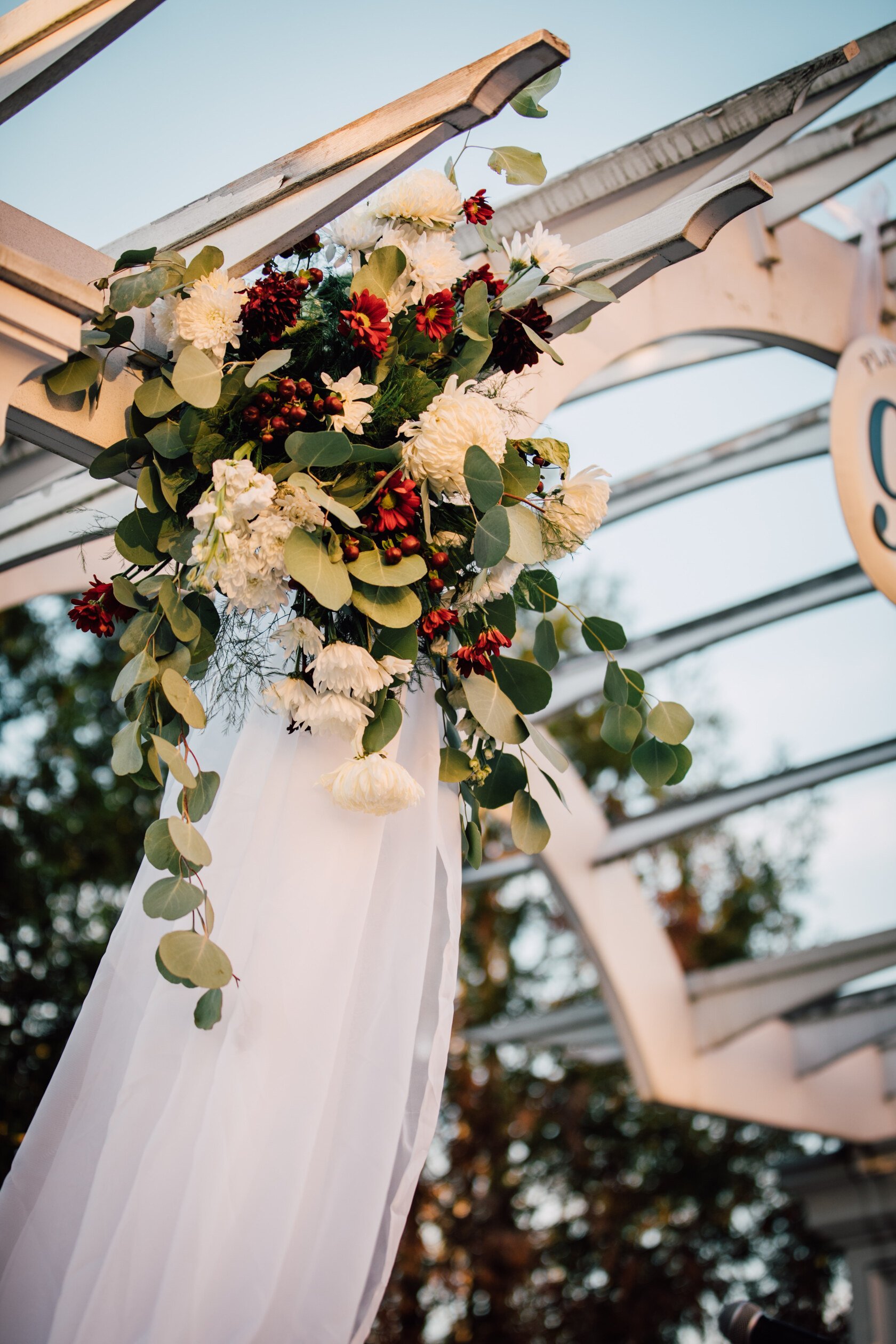  a floral arrangement sits on an outdoor arch before a harry potter wedding ceremony 