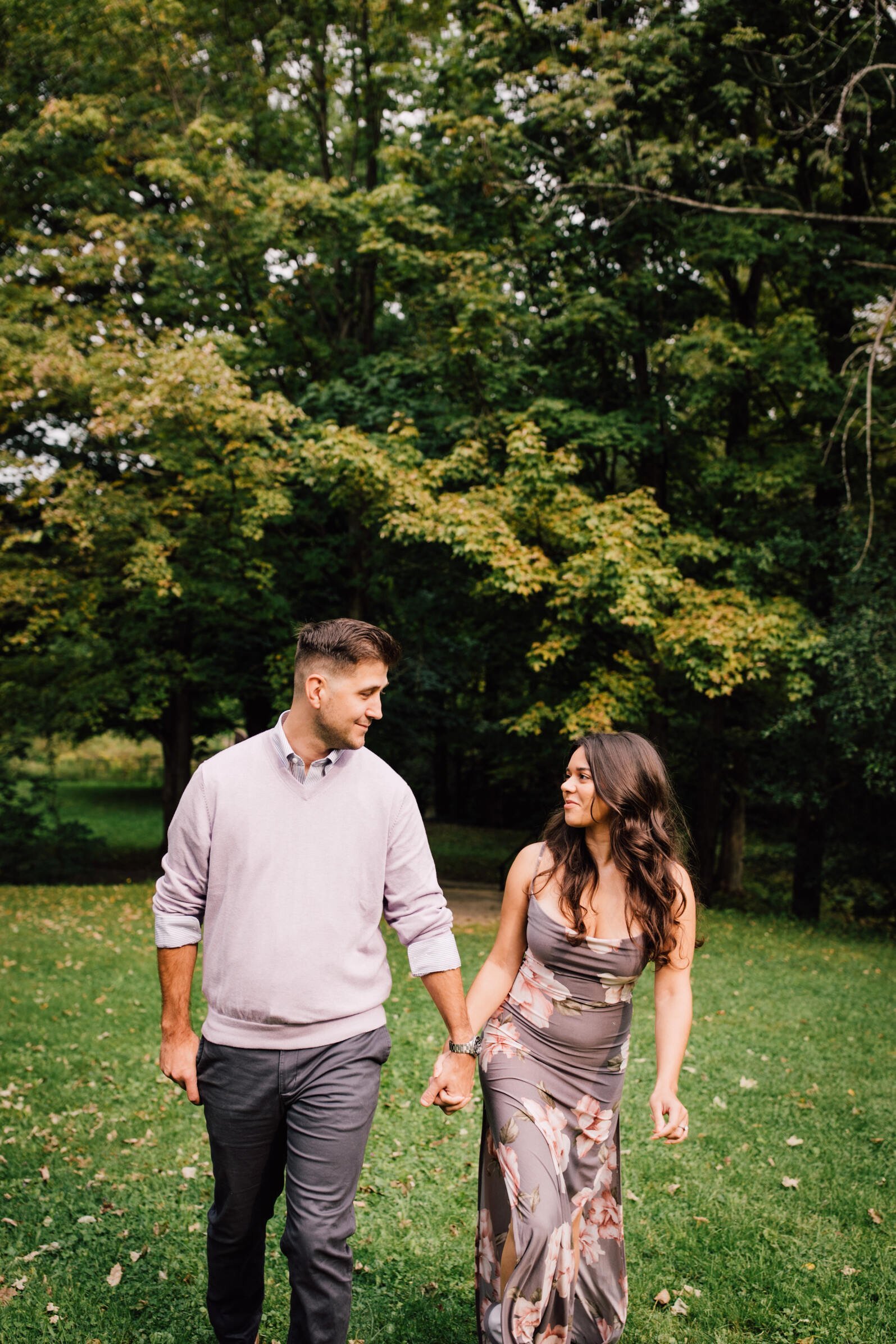  Engaged couple walks hand in hand in a grassy area, syracuse, ny 