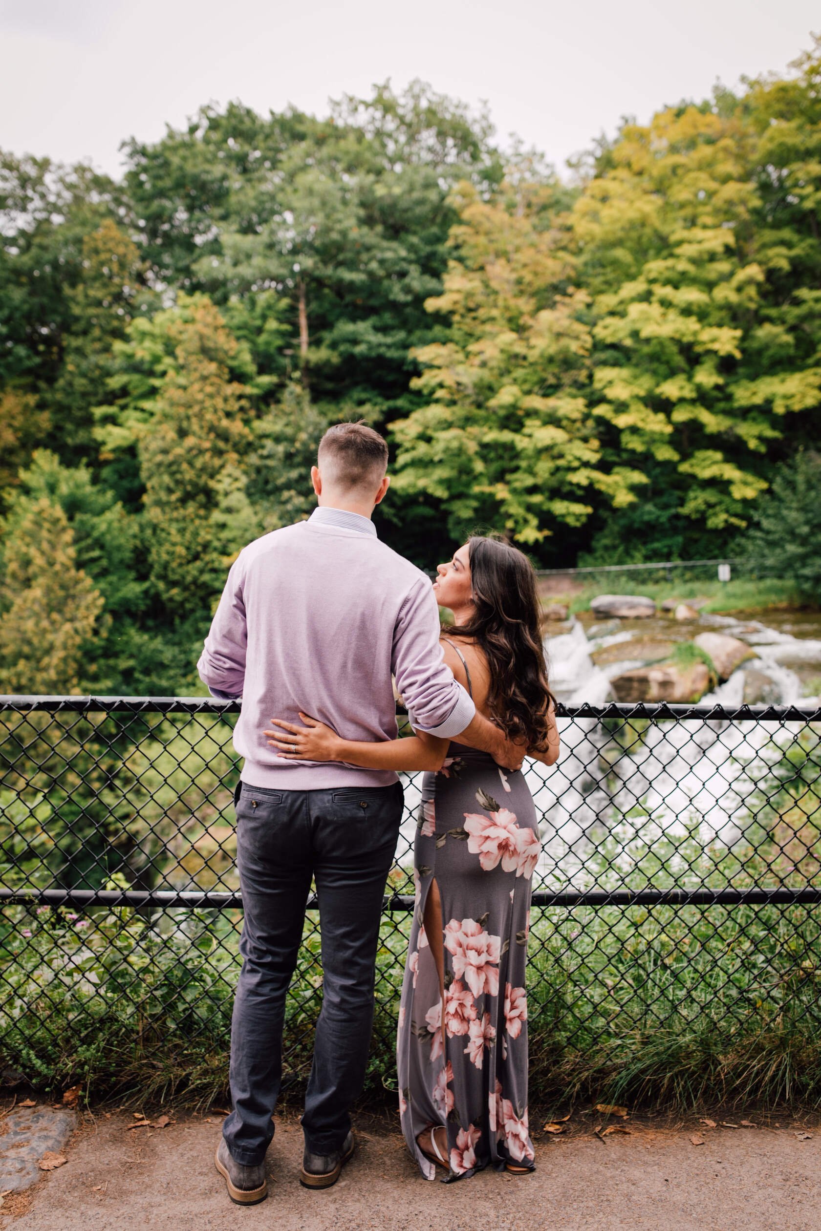  Engaged couple looks out into a nature area, waterfall engagement photos 