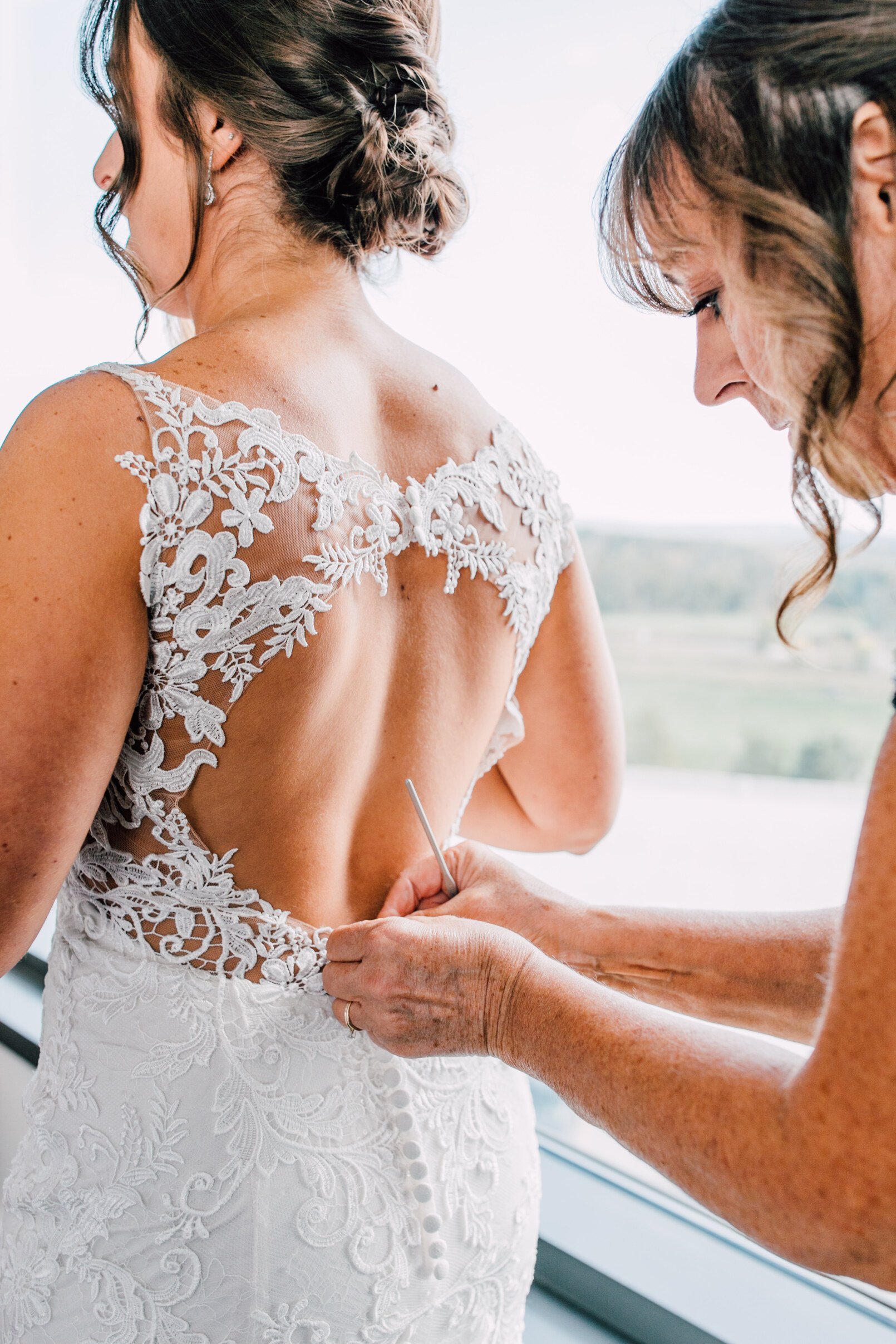  The mother of the bride buttons up the bride’s wedding dress&nbsp; 