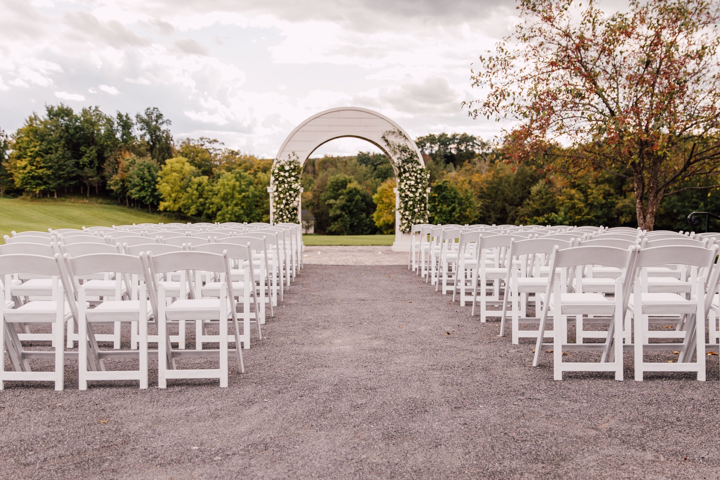  The wood wedding arch at hayloft on the arch stands in front of chairs for the wedding guests on a bright an clear day 