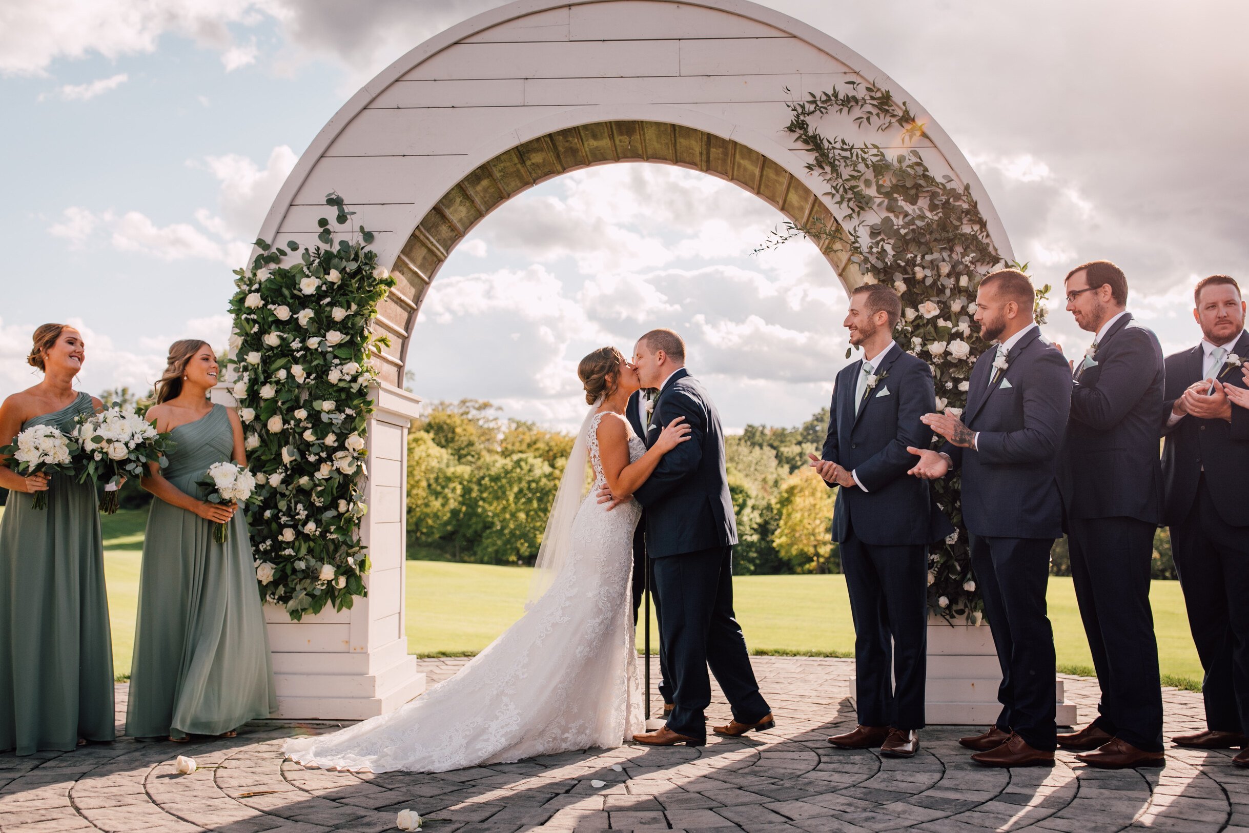  The bride and groom share a kiss under a wooden wedding arch 