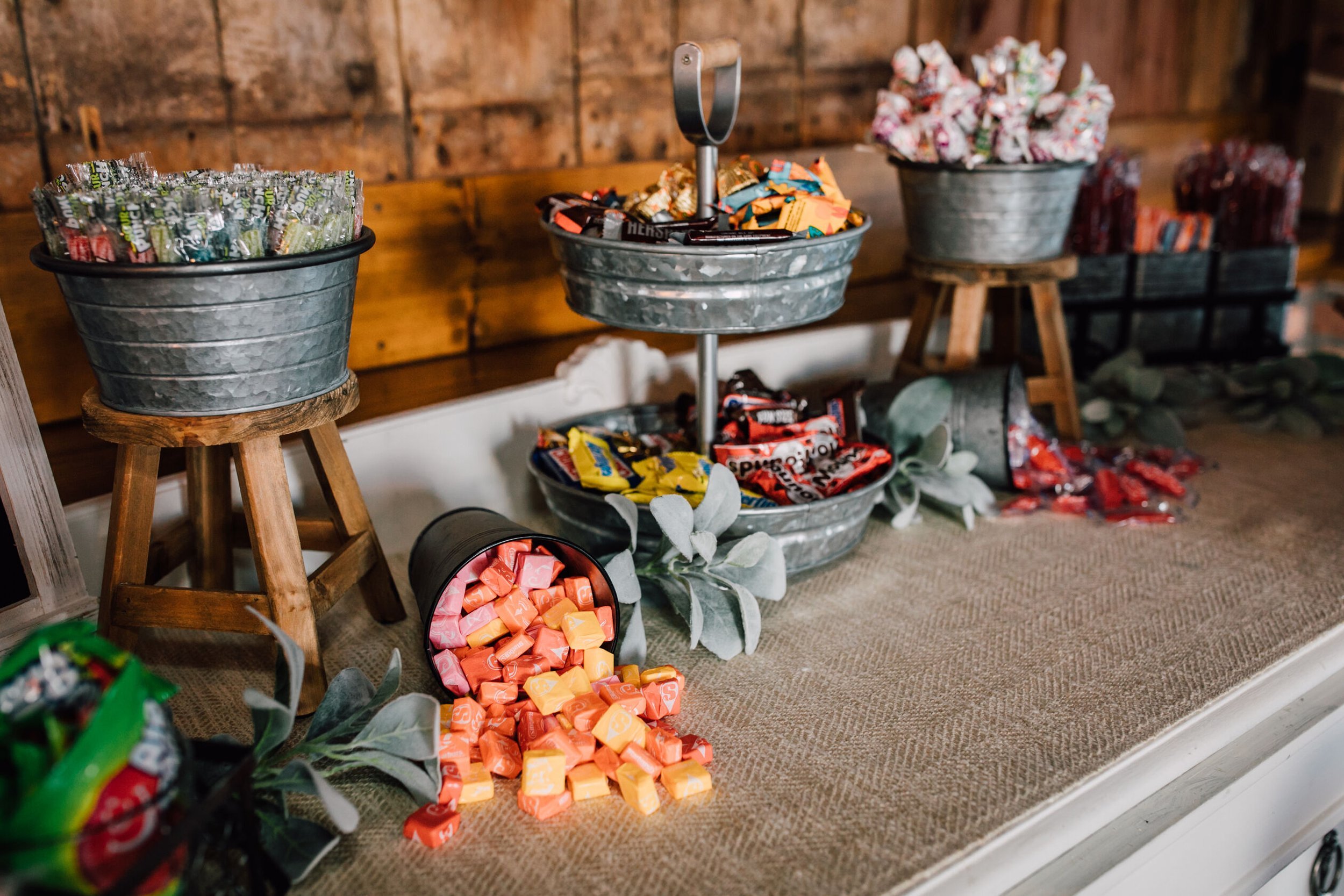  The candy buffet is sprawling with candy in galvanized steel containers for wedding guest favors 