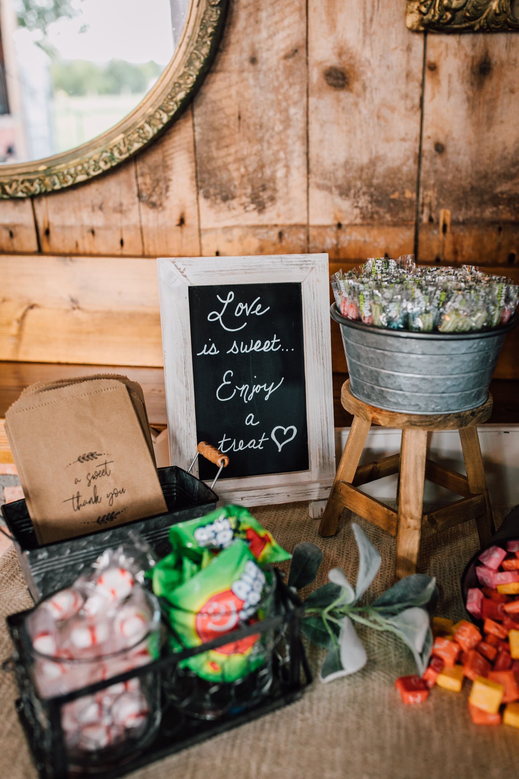  A sign for the wedding candy buffet says “love is sweet… enjoy a treat” offering candy as favors for wedding guests 