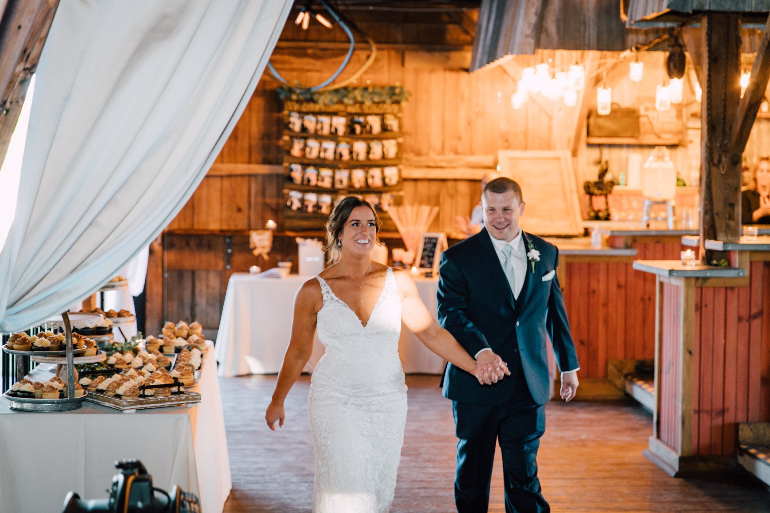  The bride and groom walk hand in hand as they are announced at their wedding reception at hayloft on the arch 