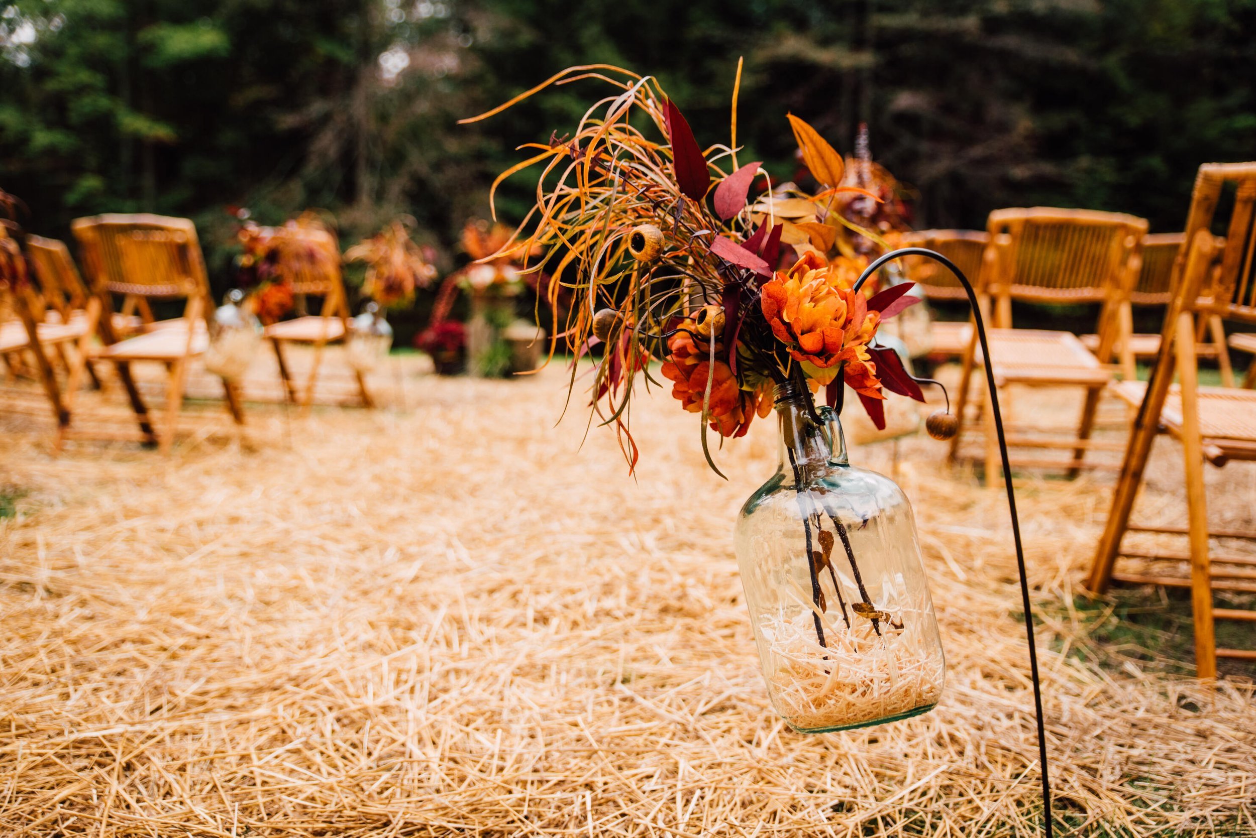  A dried bouquet hangs from a metal hanger&nbsp;at an outdoor wedding ceremony 