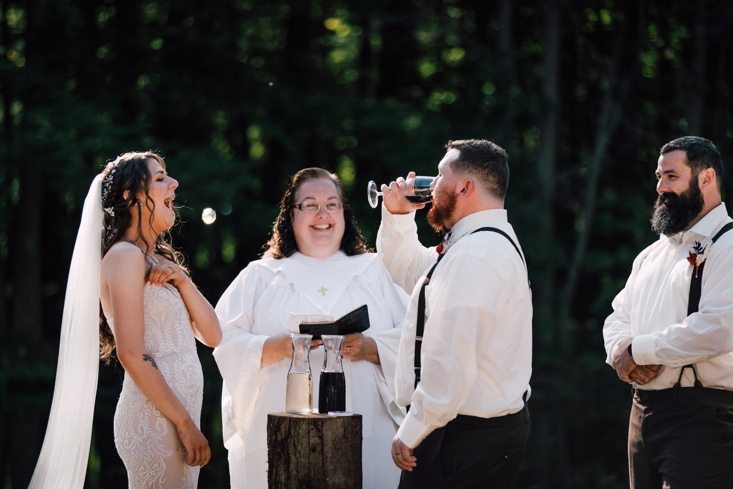  The bride laughs as the groom chugs the wine from their wine unity ceremony 