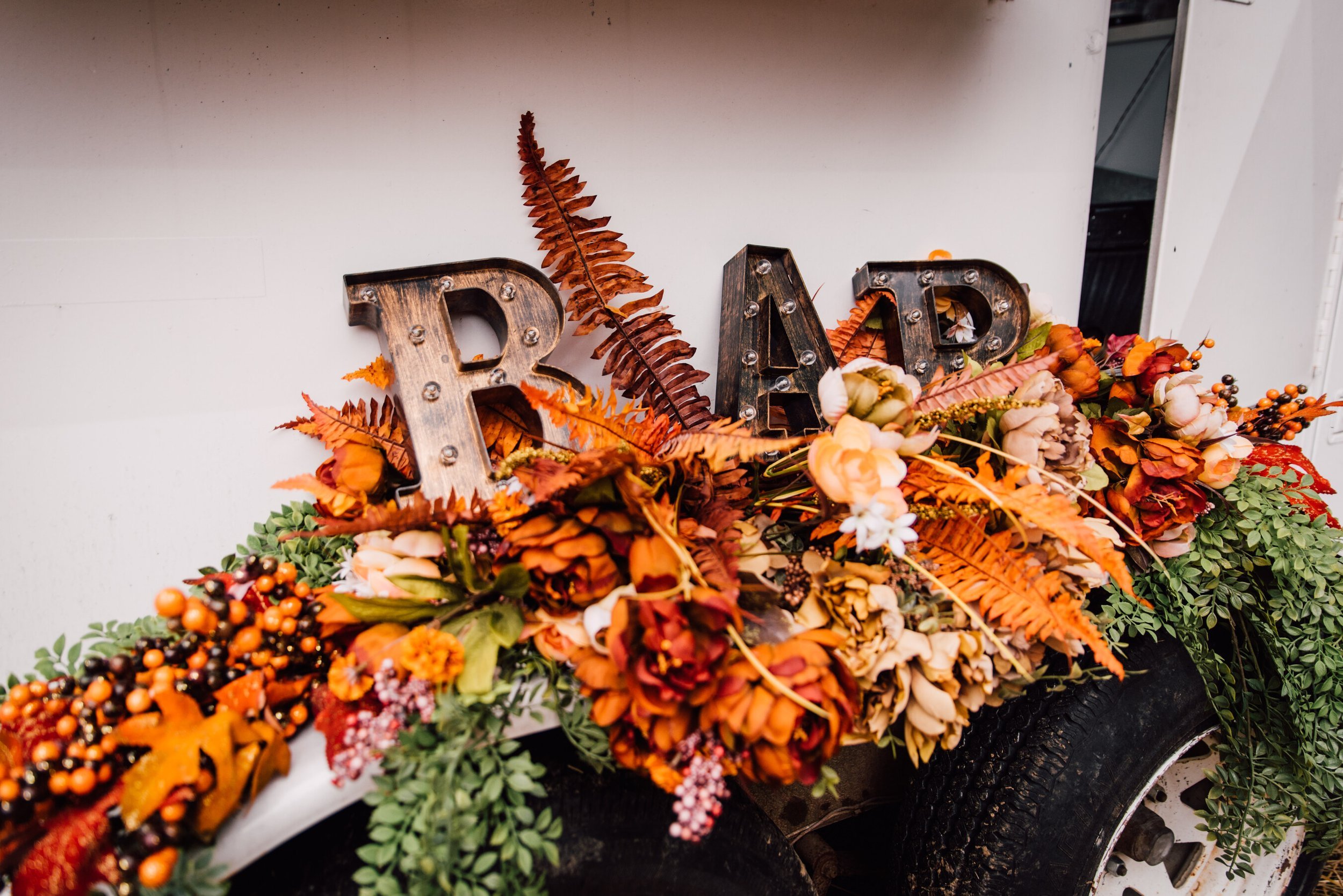 Rustic lit letters that spell out bar sit on top of a dried floral arrangement as part of the backyard wedding decor&nbsp; 