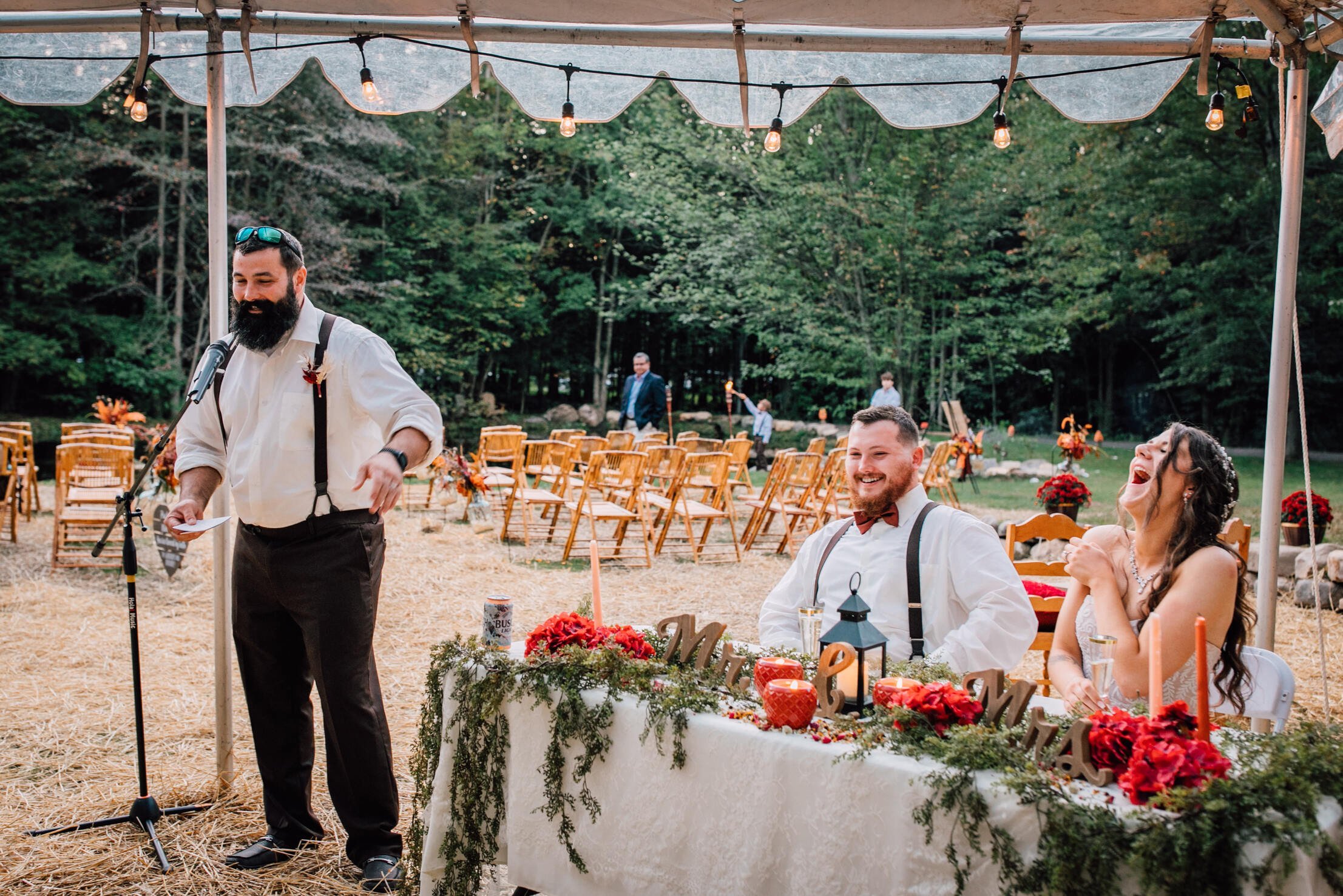  The best man gives a toast at a rustic wedding under a clear tent 