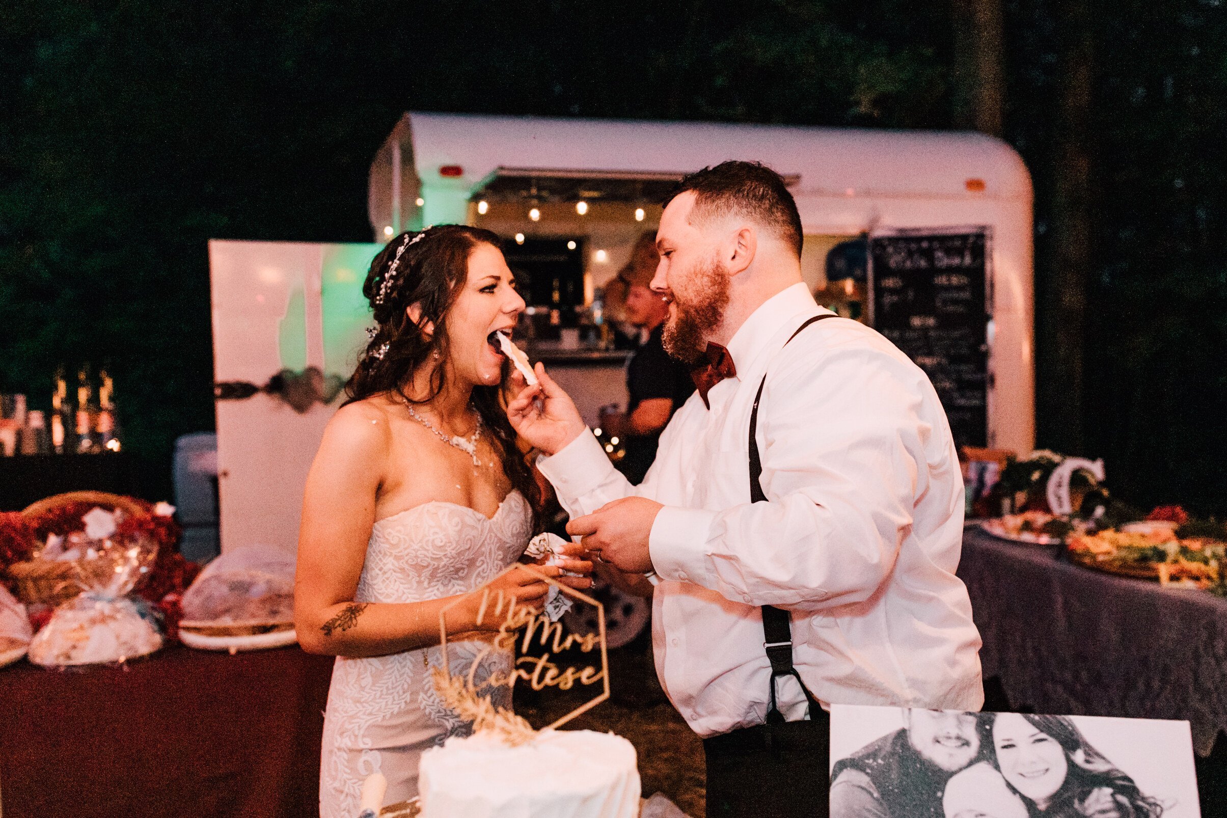  The groom feeds the bride a piece of cake at their backyard wedding reception 