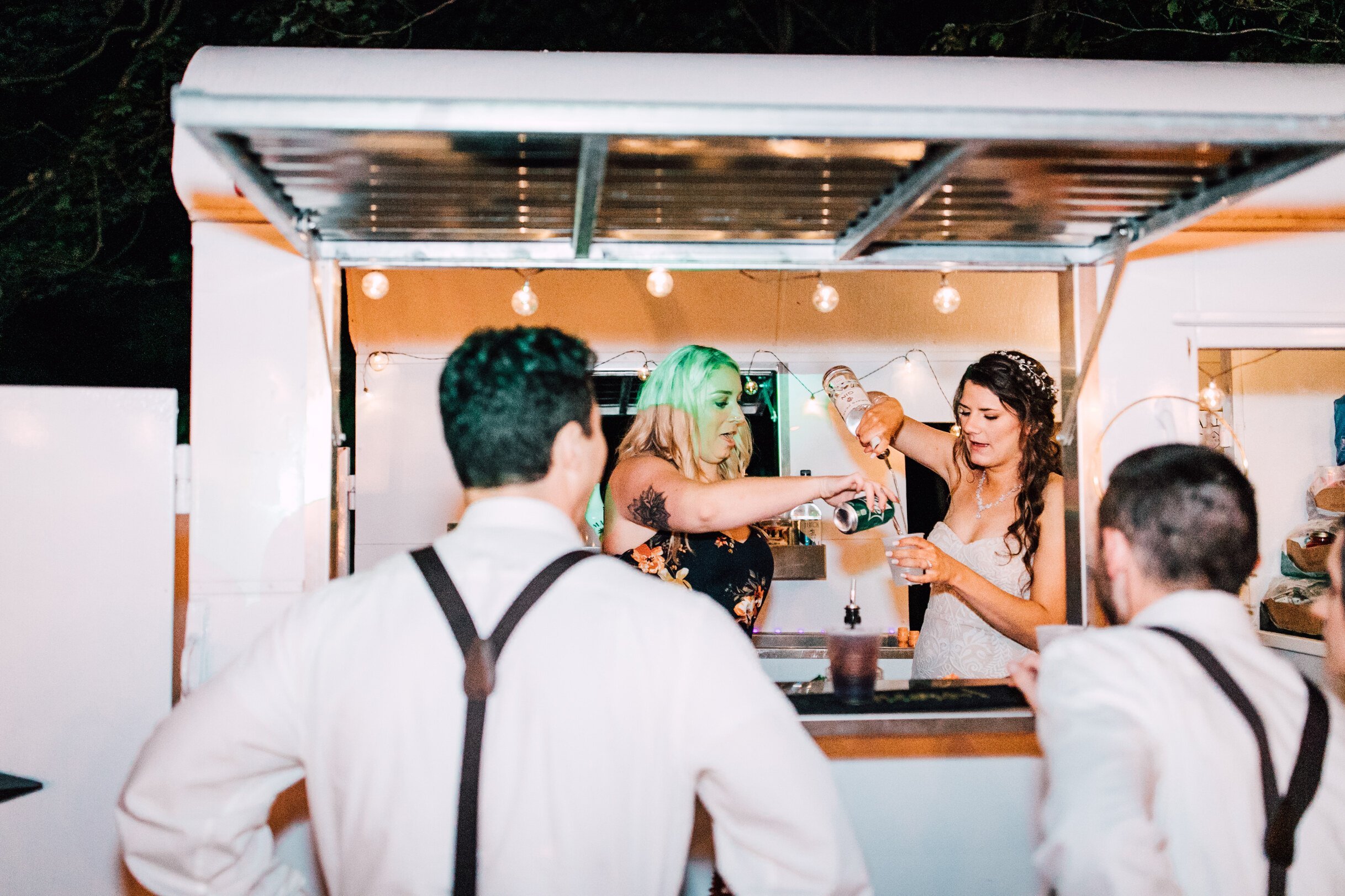  The bride helps serve drinks in a mobile bar at her outdoor fall wedding 