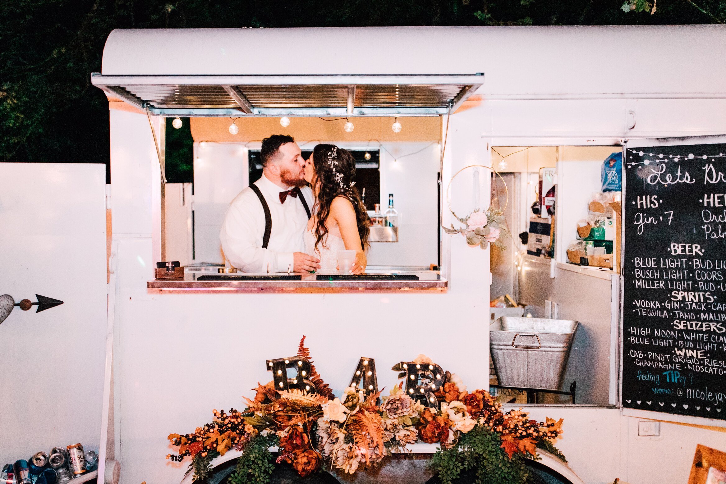  The bride and groom share a kiss inside the mobile bar at their rustic wedding reception 