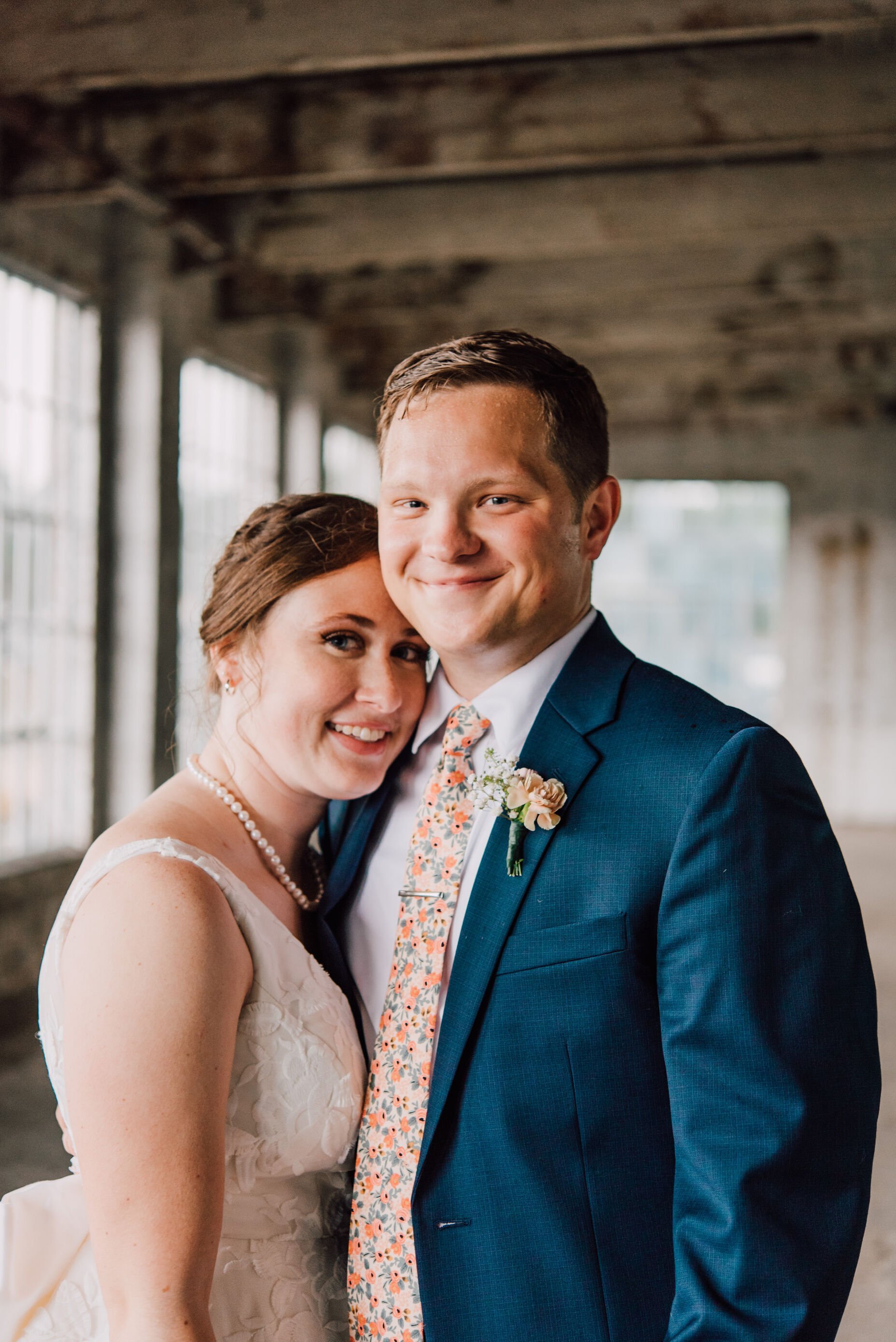  Bride and groom smile at their photographer at their warehouse wedding 