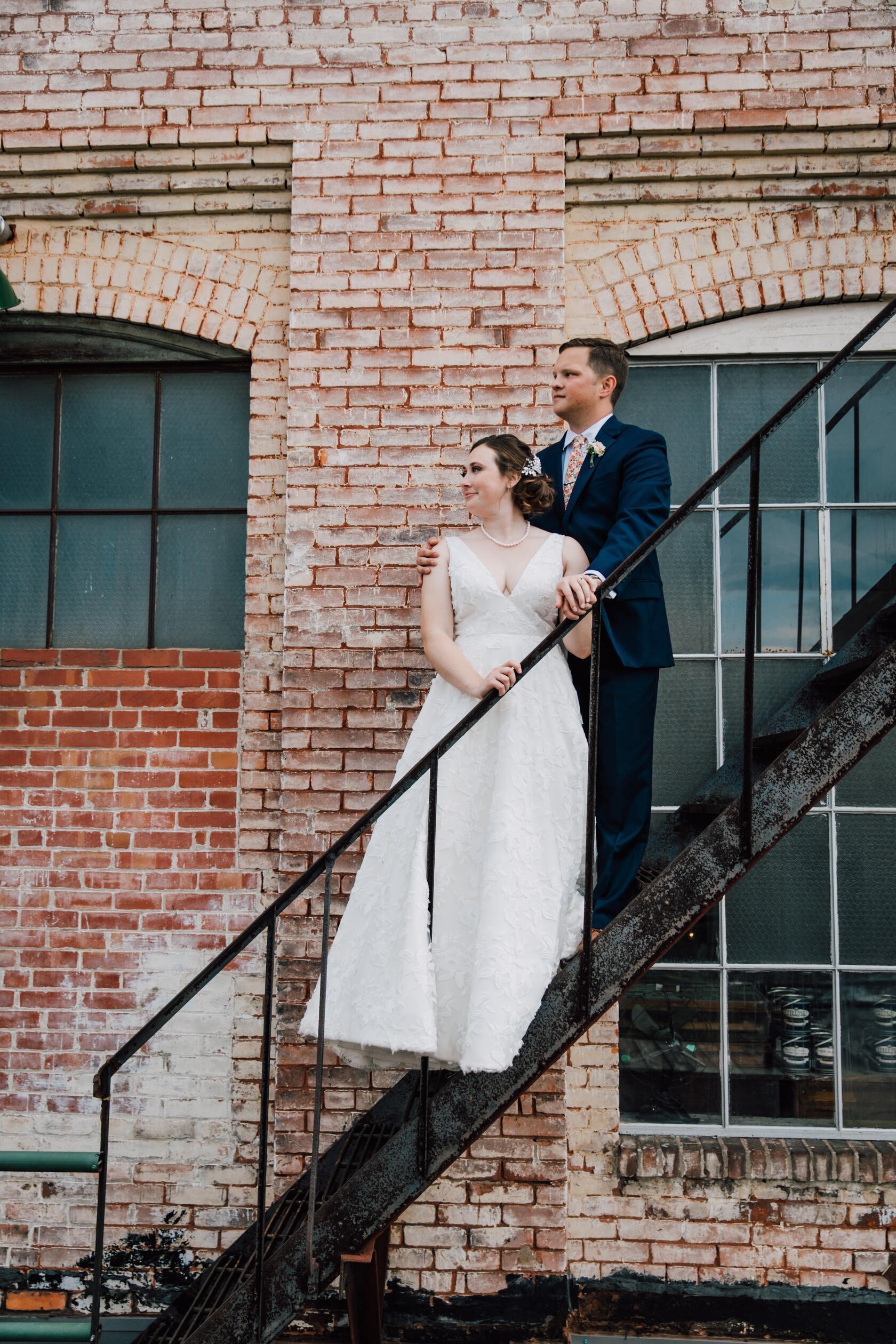  Bride and groom stand together on an industrial staircase after their vow renewal 
