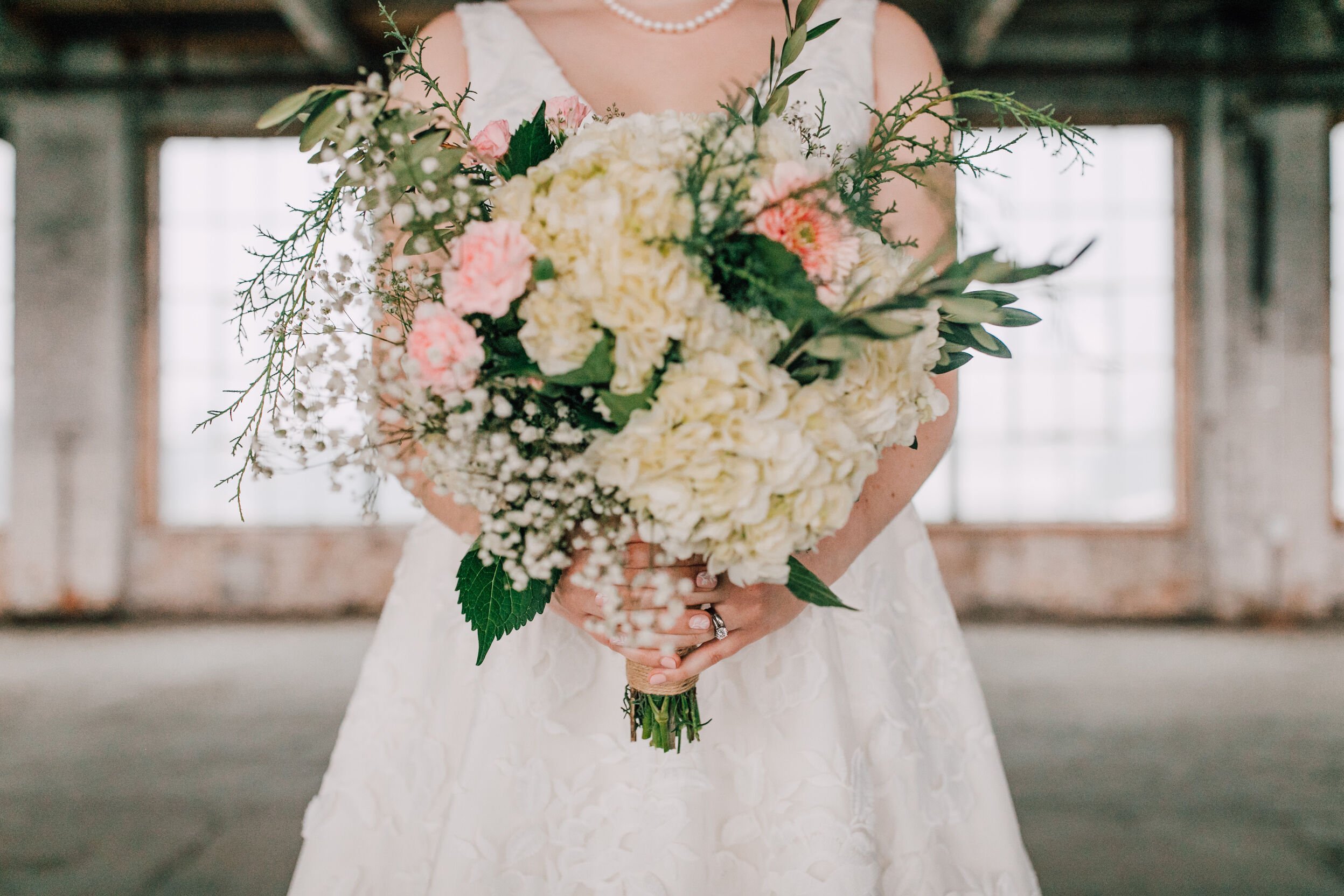  Bride holds her bouquet at her industrial wedding venue&nbsp; 