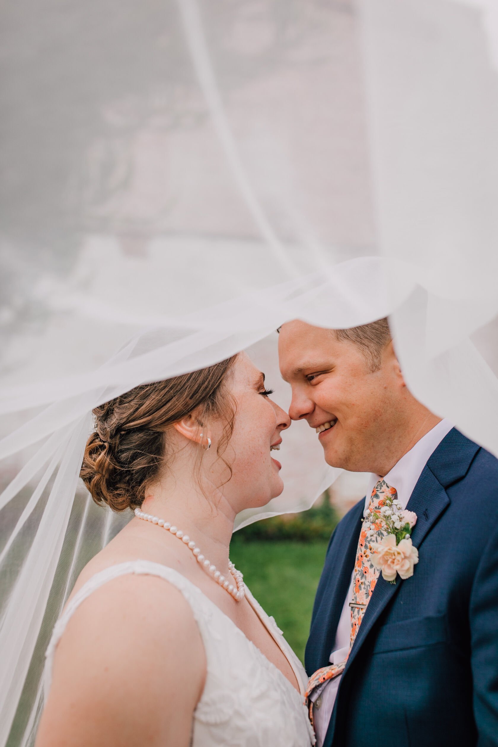  Bride and groom look at each other under the bride’s veil at their vow renewal 