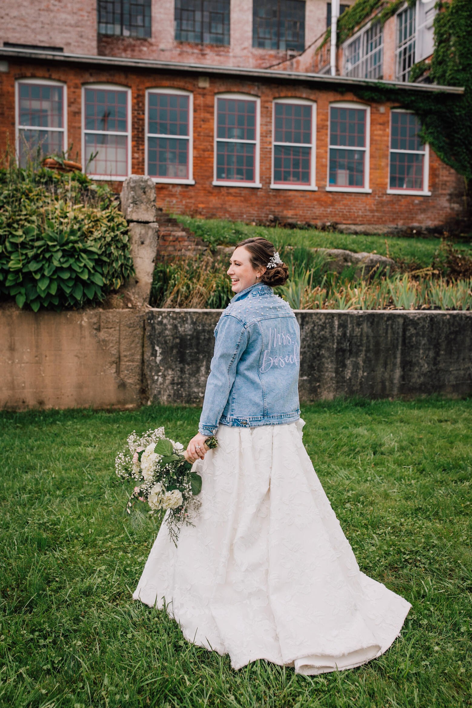  Bride stands in her custom wedding jean jacket at her cracker factory reception 