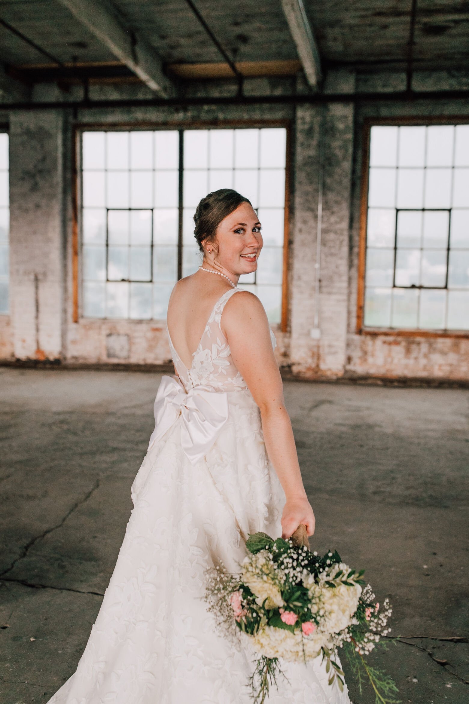  Bride looks over her shoulder at her industrial wedding venue 