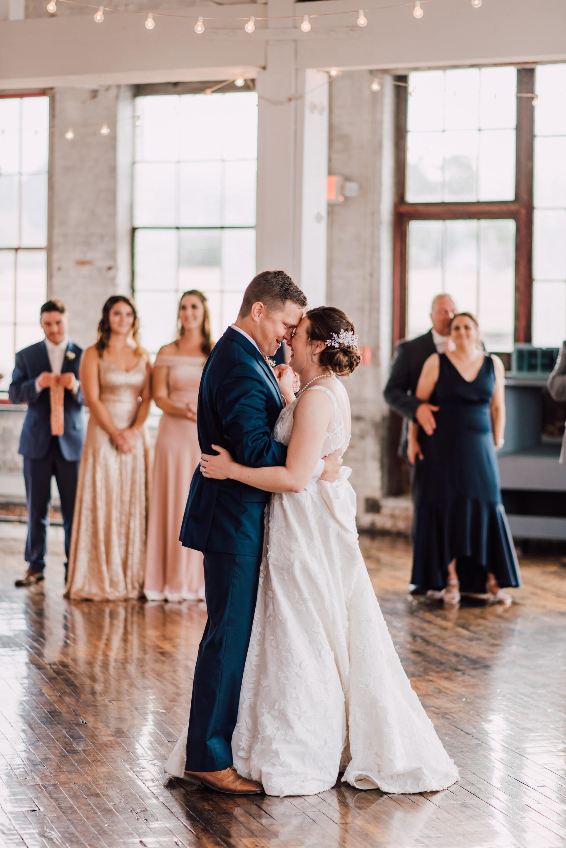  Bride and groom look at each other during their first dance at their industrial wedding venue 