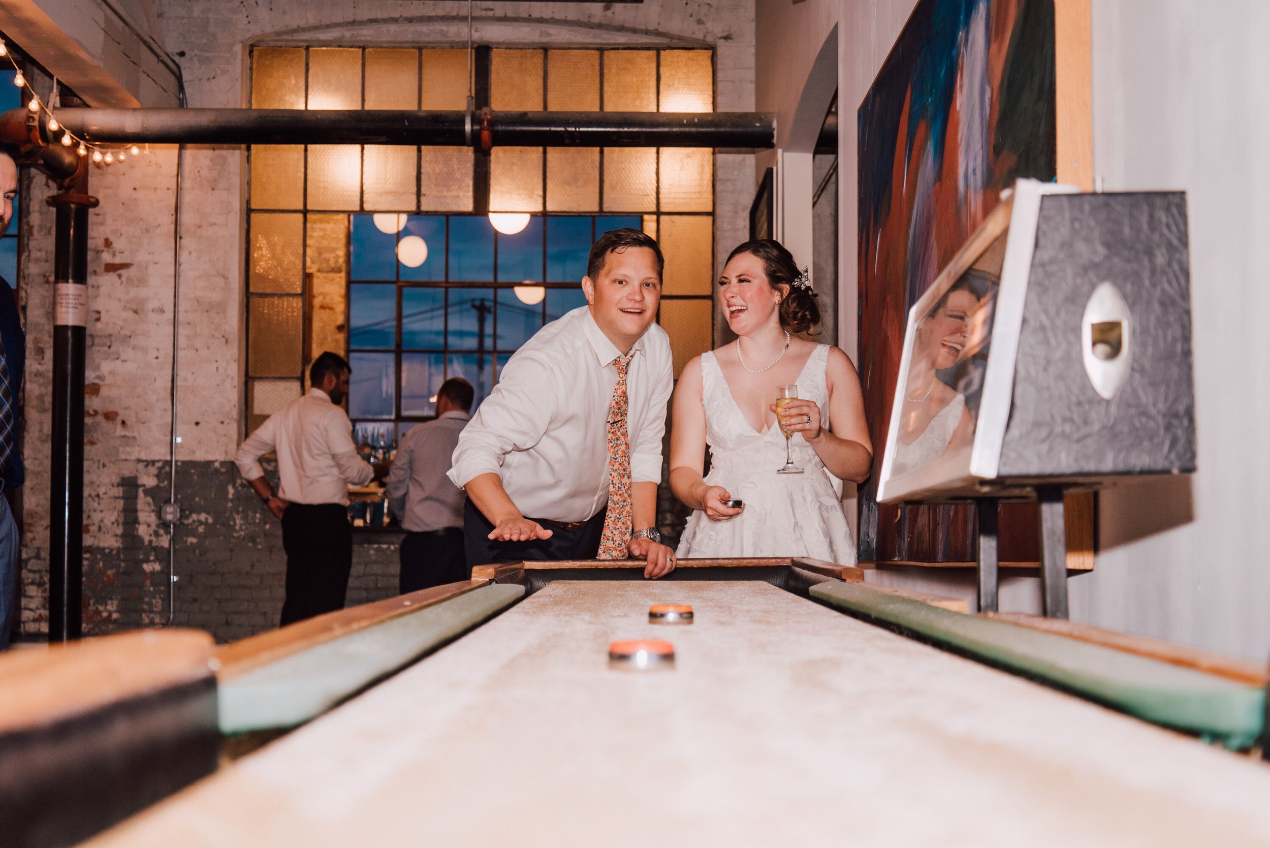  Bride and groom play shuffleboard at their warehouse wedding reception in Geneva ny 