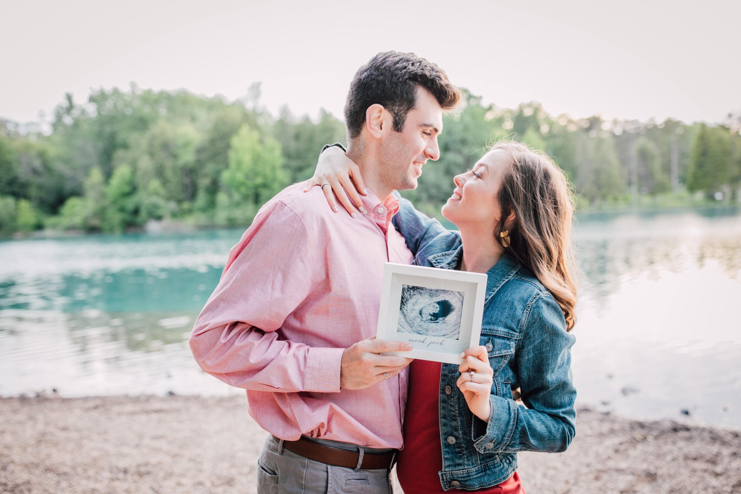  Mom and dad to be hold ultrasound photo while looking at each other for their pregnancy announcement 