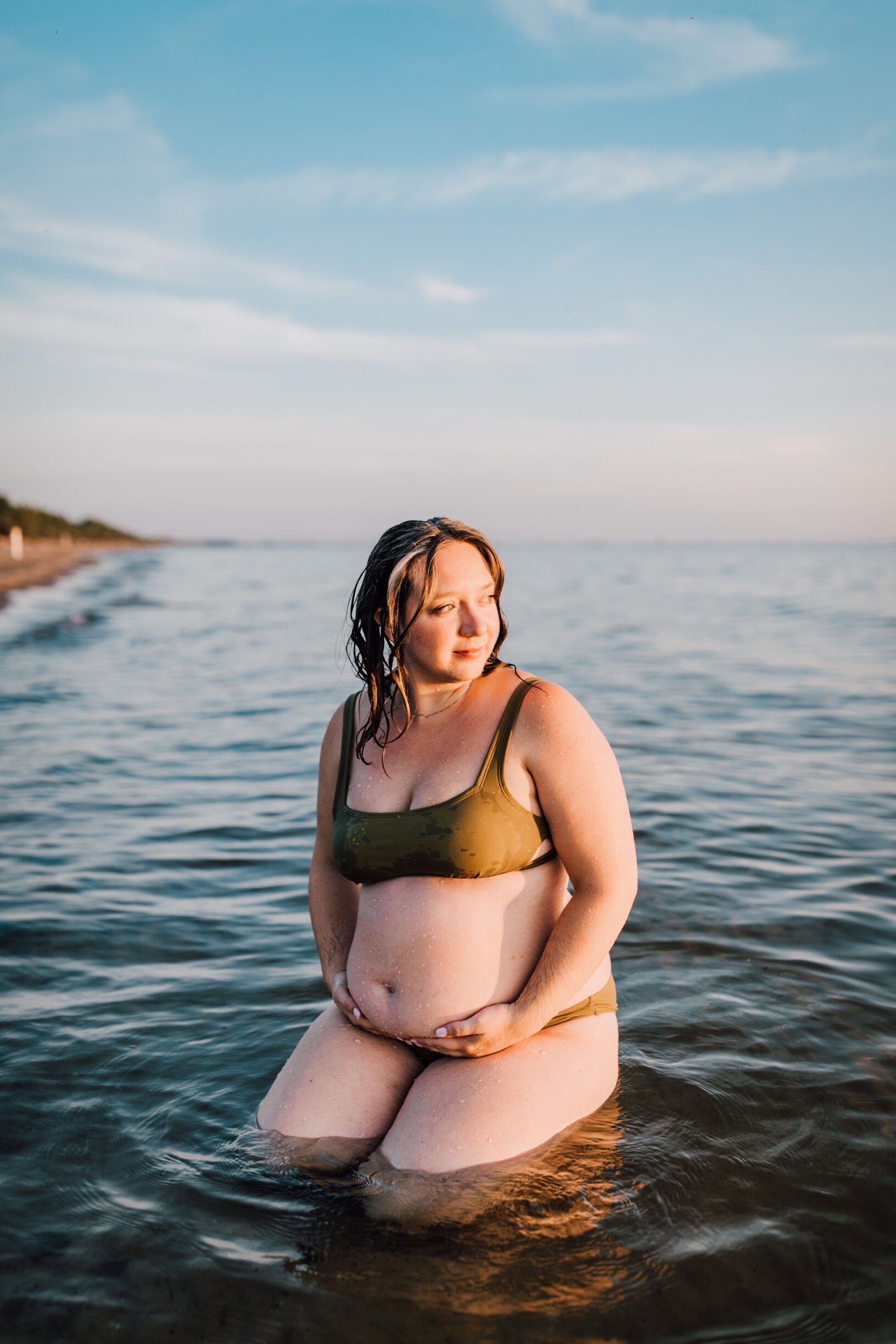  A woman looks off to the side during her maternity photoshoot, southwick beach 