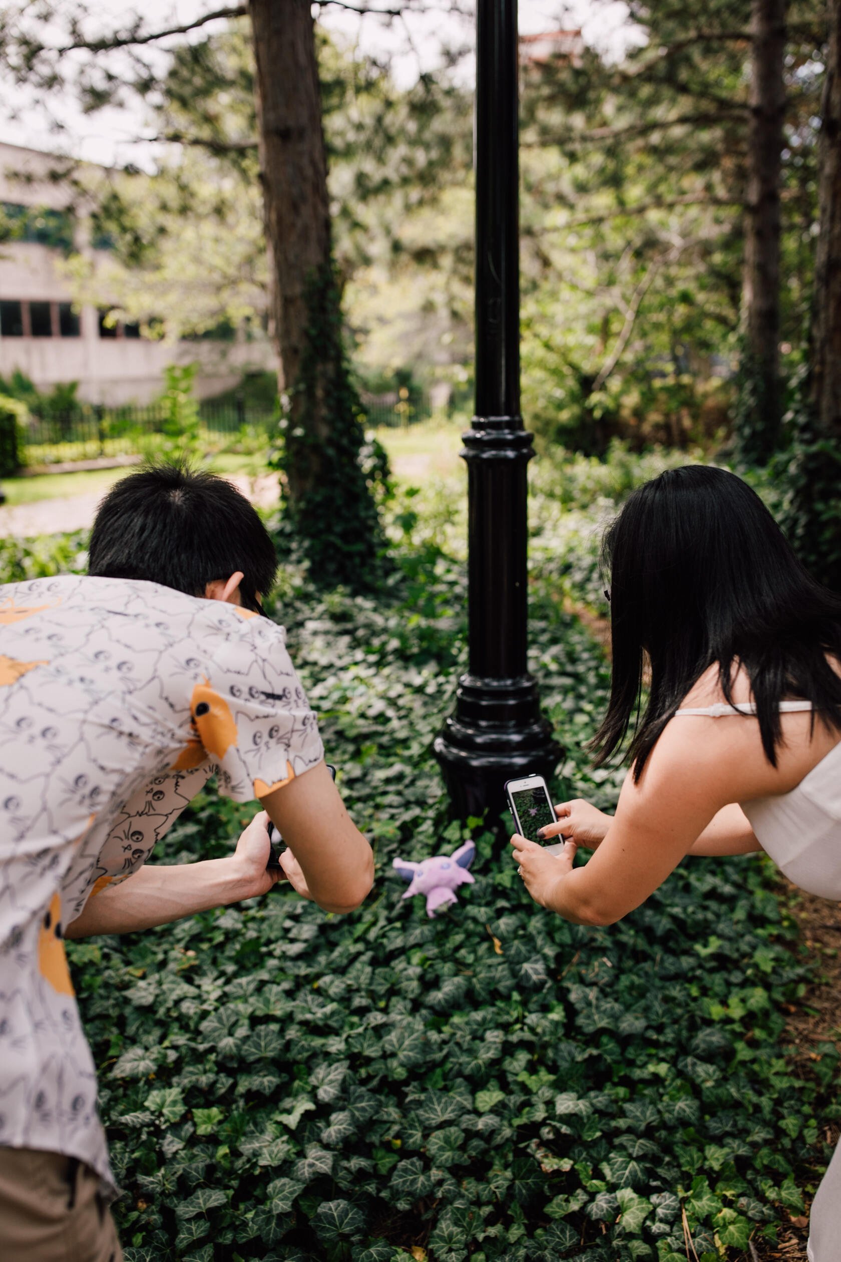  An engaged couple play pokemon go together in a park, nerdy engagement photos 