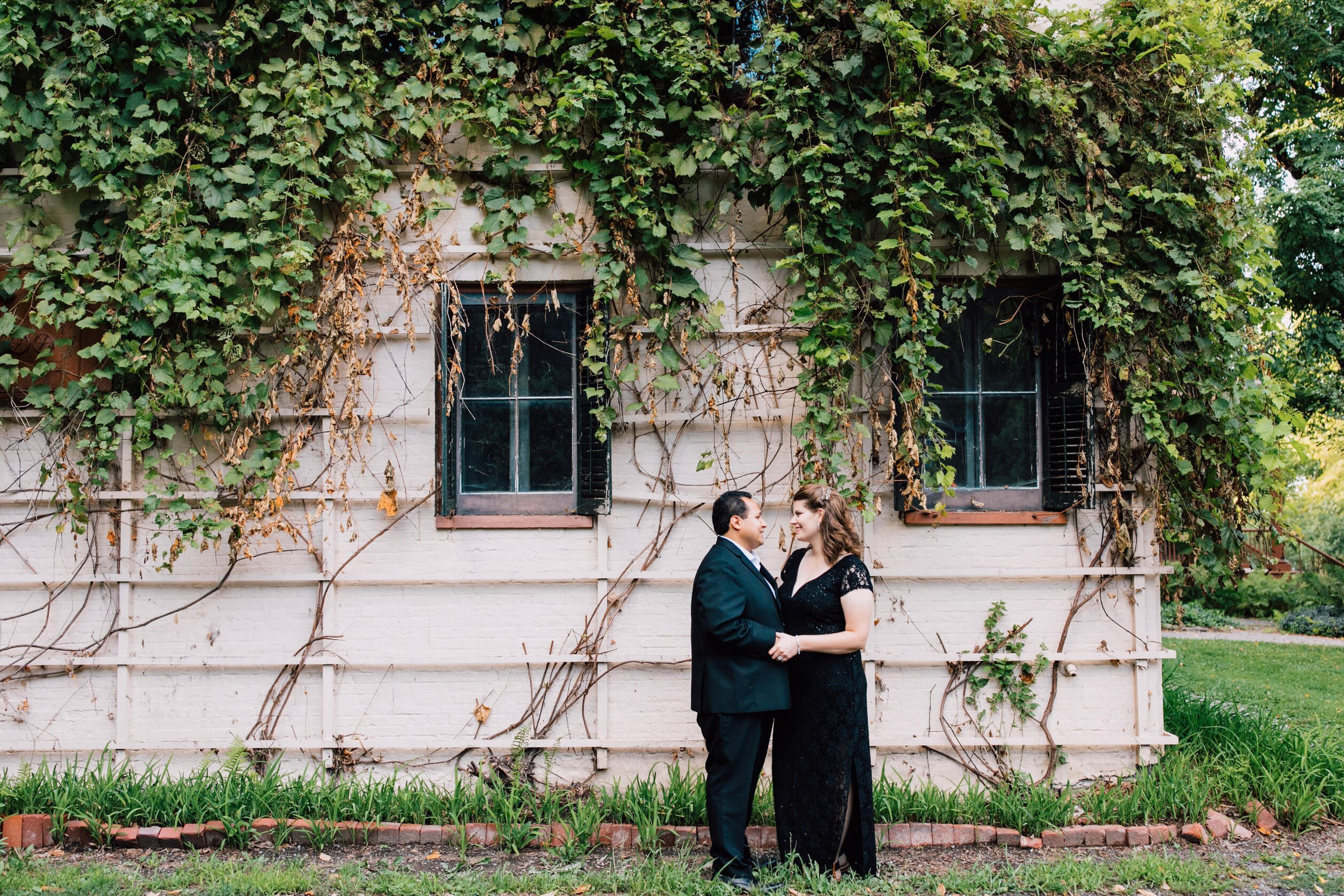  Married couple beam at each other as they stand in front of a building on the site of Lorenzo state historic site 