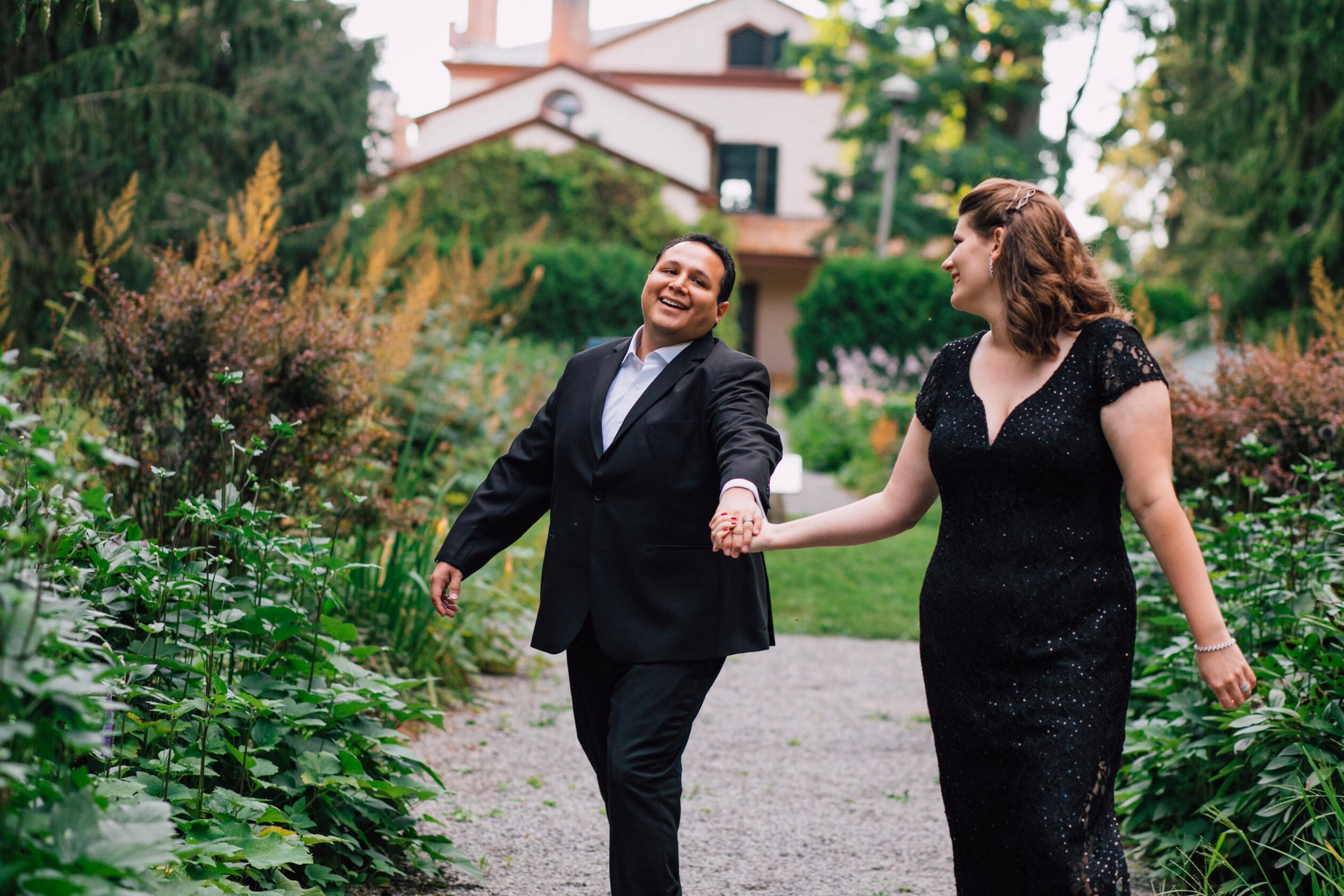  Elizabeth looks back at her husband as they walk hand in hand in hand down a garden path during their anniversary photoshoot 