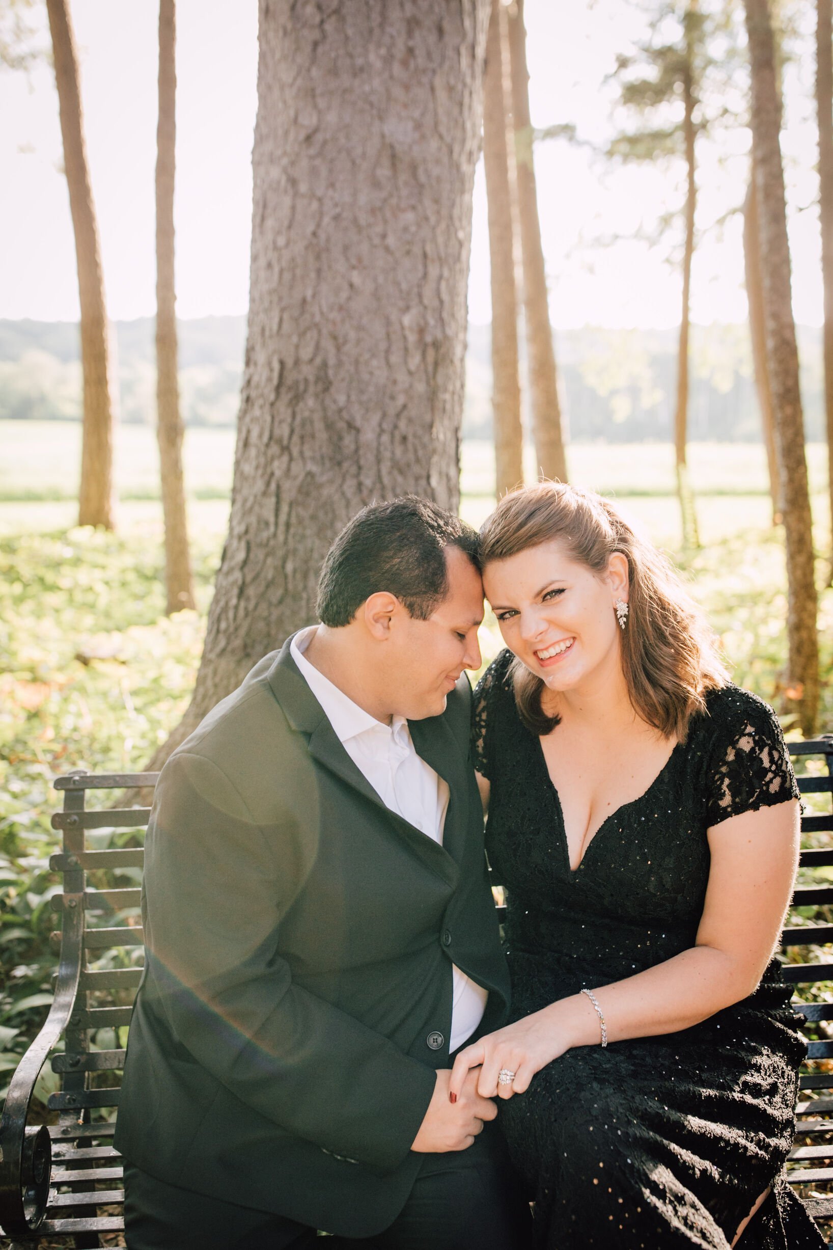  a married couple sit together on a bench in the wood for their first anniversary photos 