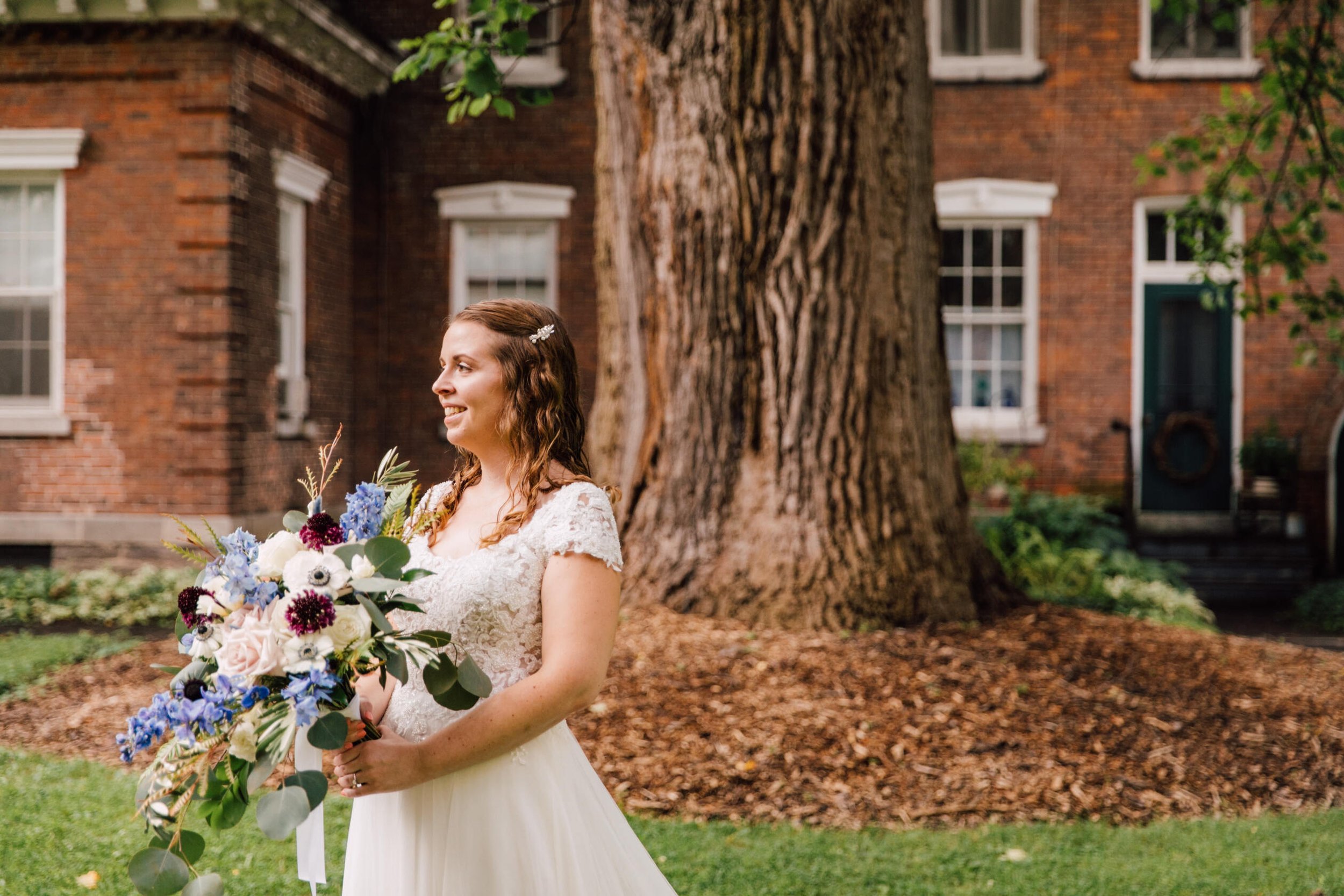  Bride stands with florals in hand moments before the ceremony at oneida community mansion house 