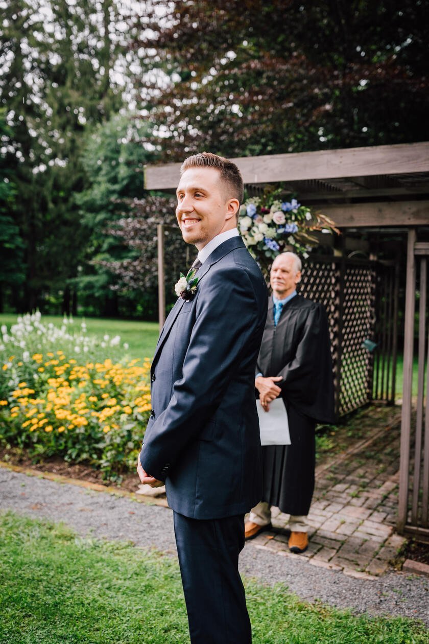  Groom watches his bride walk towards him at their garden wedding ceremony 