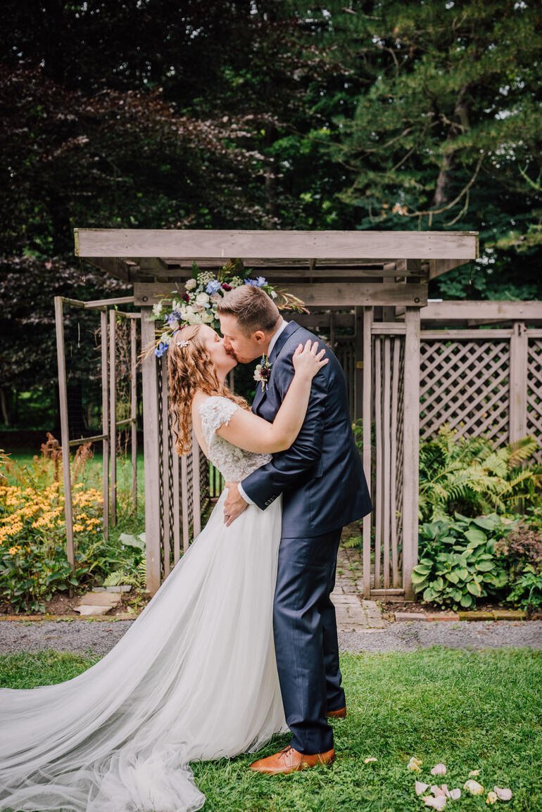  Bride and groom take their first married kiss at their outdoor wedding ceremony 