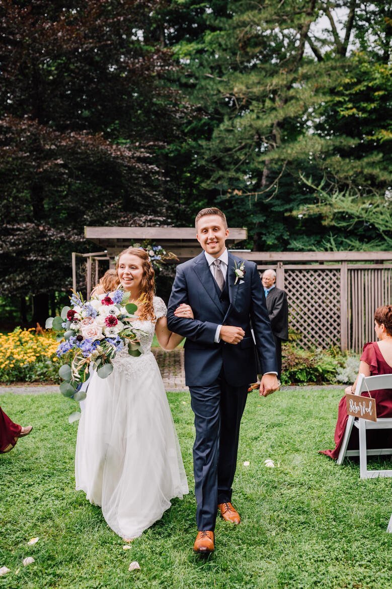  Bride and groom walk down the aisle together at the end of their outdoor wedding ceremony 
