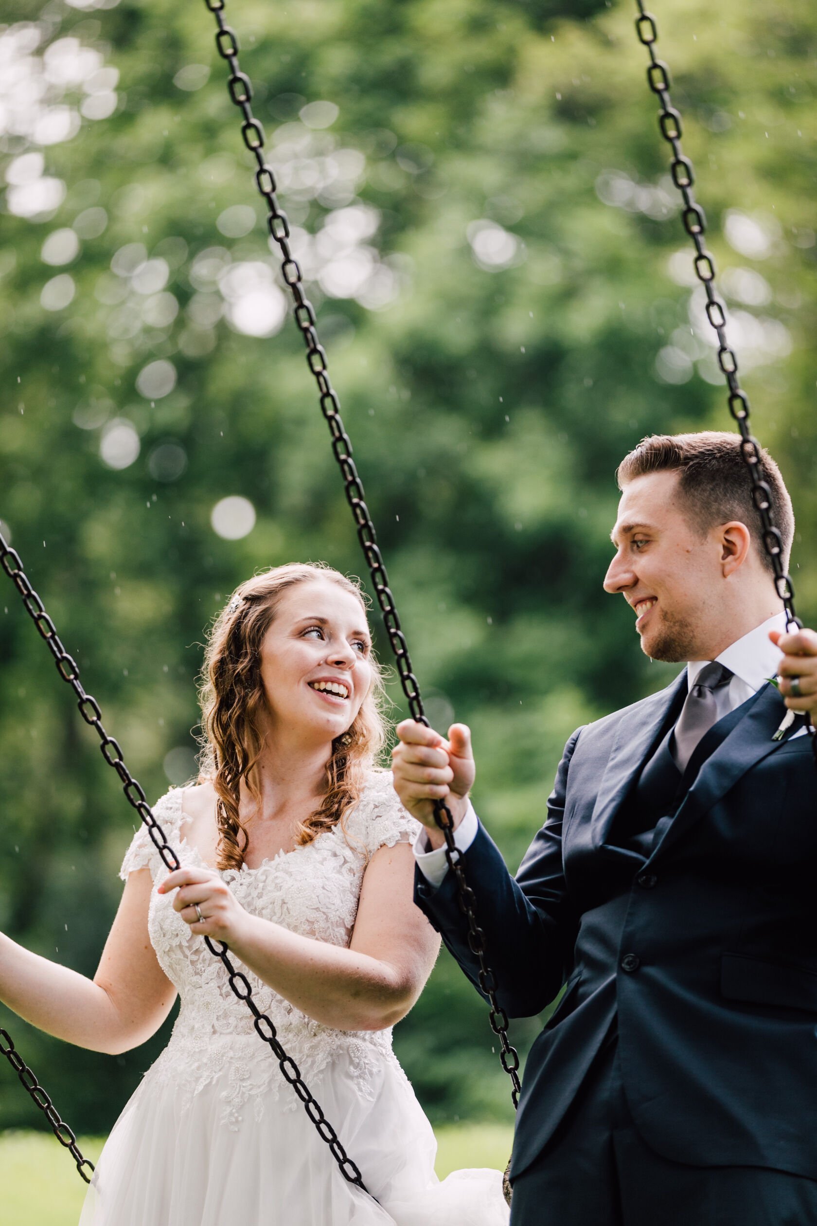  Bride and groom look at each other while on swings during wedding portraits at oneida community mansion house 