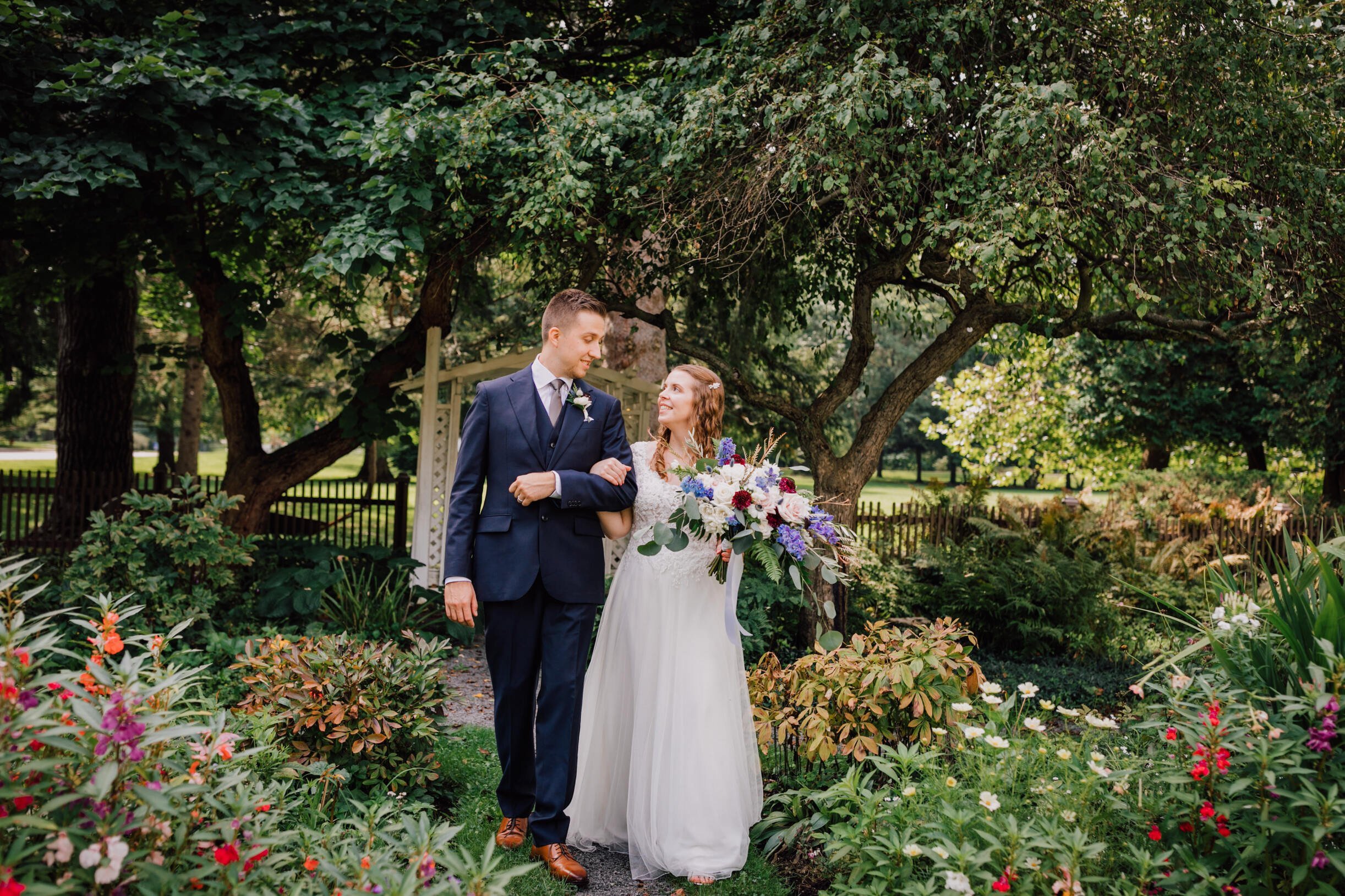  bride and groom look at each other among flowers at their new york garden wedding 