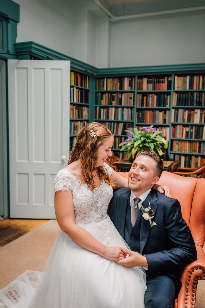  Bride and groom look at each other in the library of oneida community mansion house 